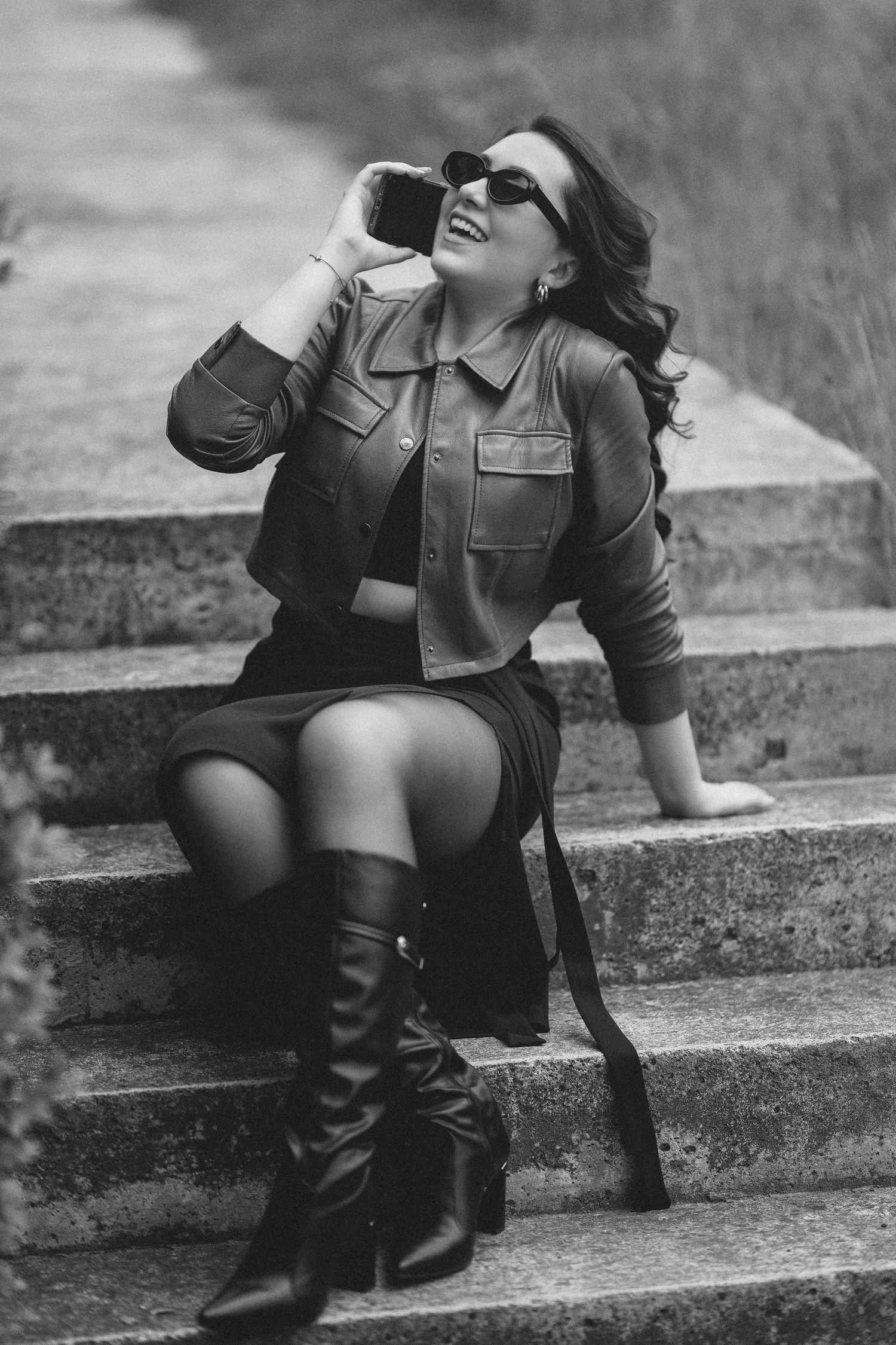 A black and white photo series shows someone sitting on concrete steps wearing boots and sunglasses.