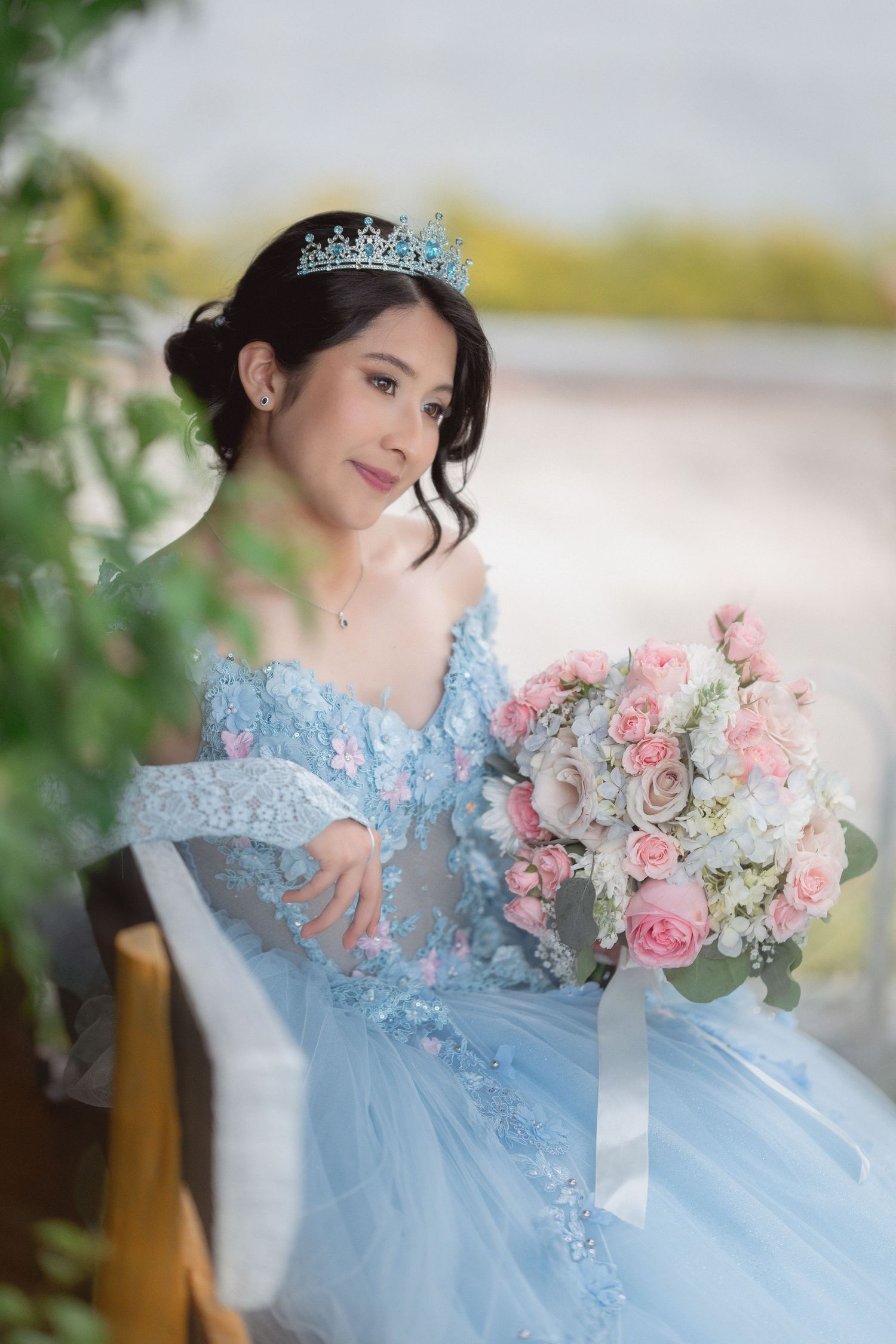 A dreamy photoshoot featuring a light blue tulle gown with floral appliques and a pink and white rose bouquet.