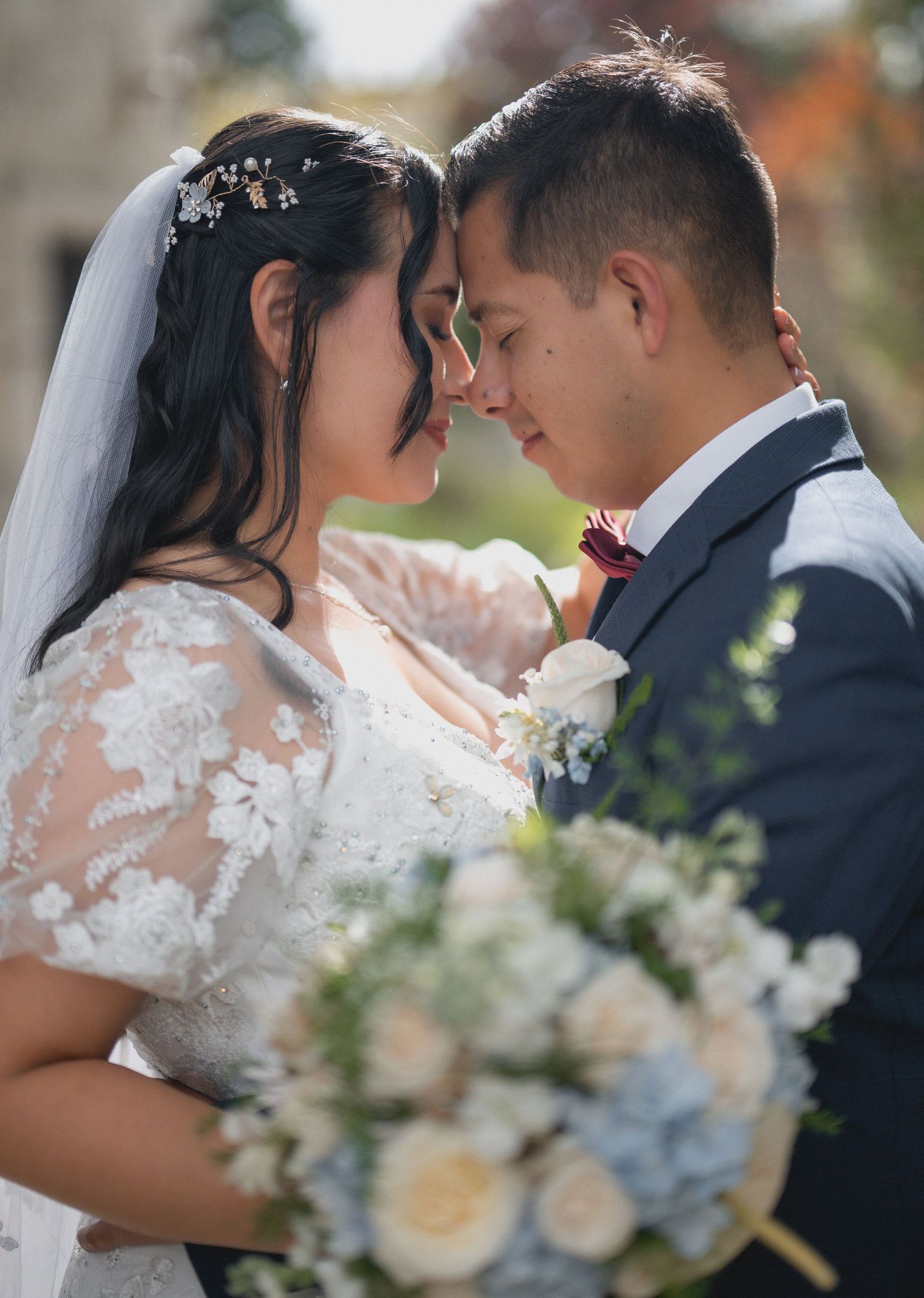 Romantic wedding couple shares intimate moments while holding a bouquet of white and blue flowers.