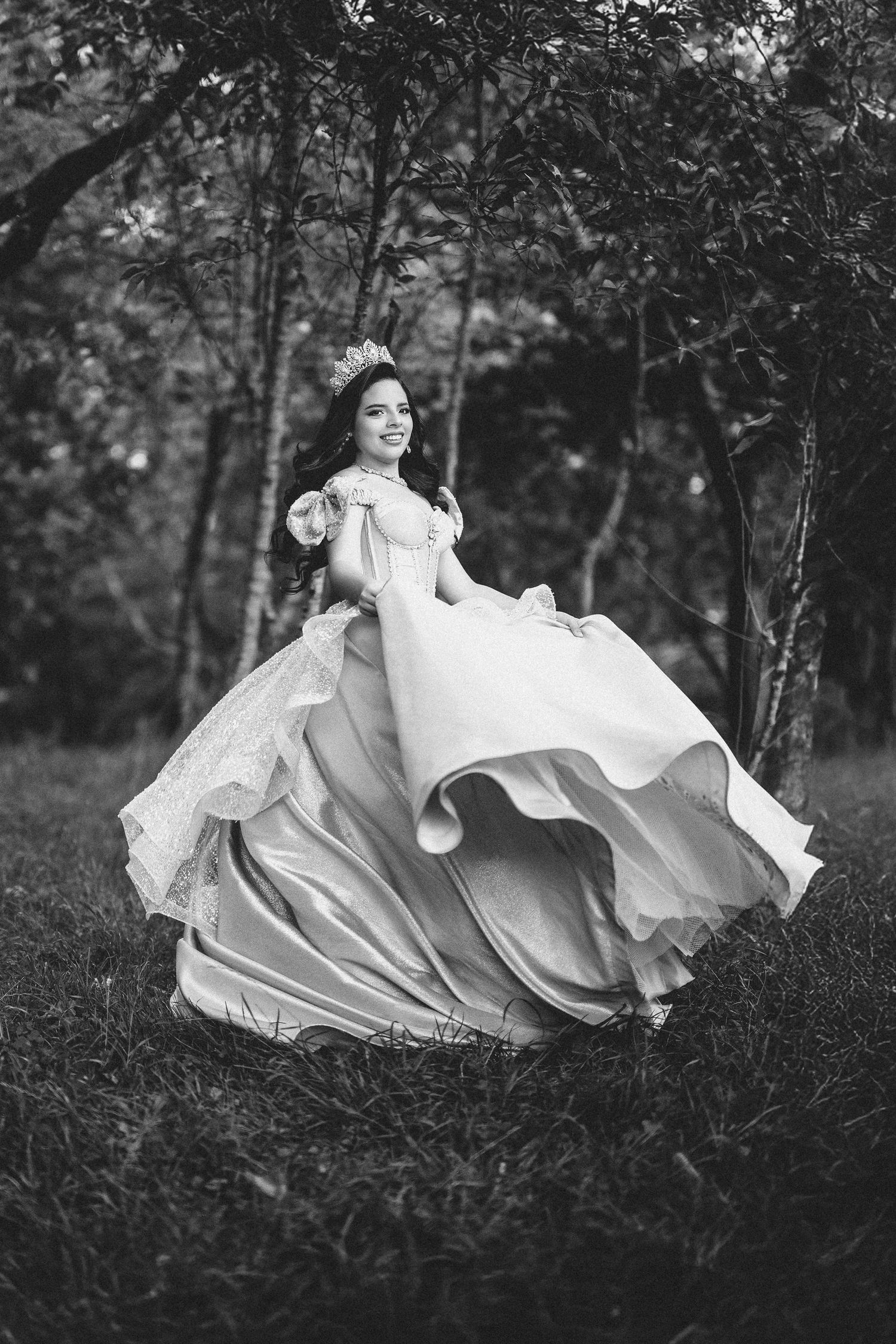 A flowing white dress billows dramatically in a series of artistic black and white photographs taken in a wooded setting.