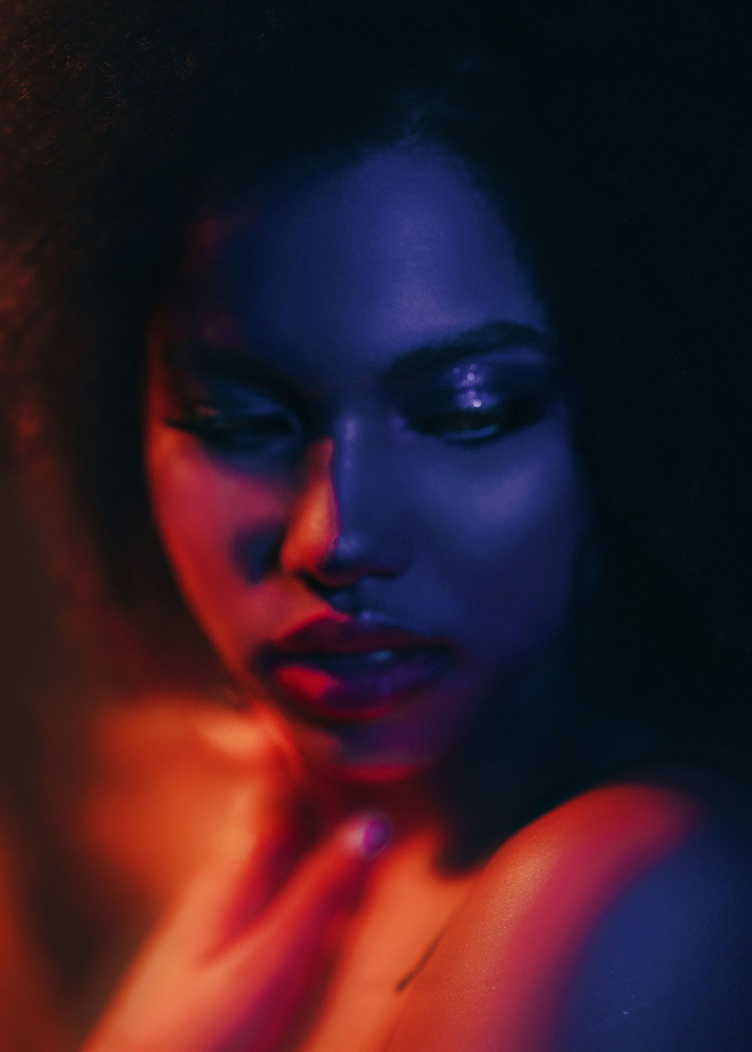 Artistic portrait series showing a face illuminated by dramatic red and blue lighting in a dark moody setting.