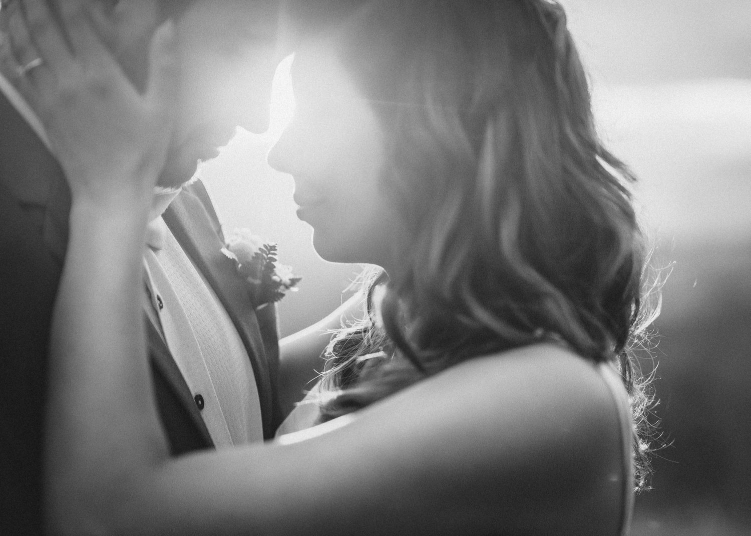 Black and white close-up shot of an intimate moment between a couple with soft lighting.