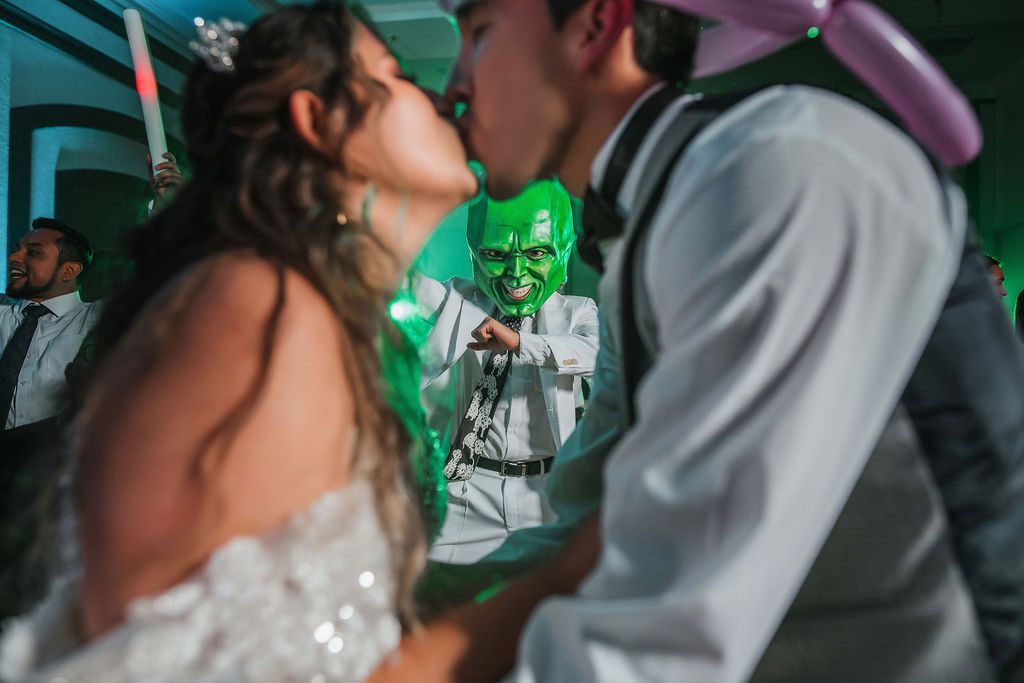 Couple dancing together at a wedding reception with green ambient lighting.