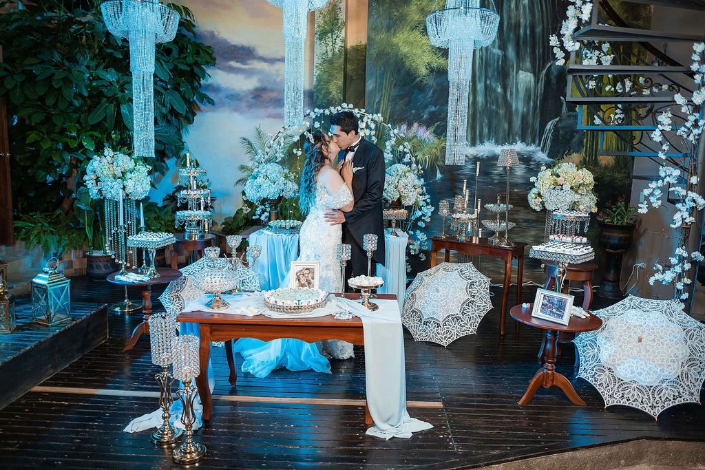 Elegant outdoor wedding reception setup with blue lighting and white decorations at dusk.
