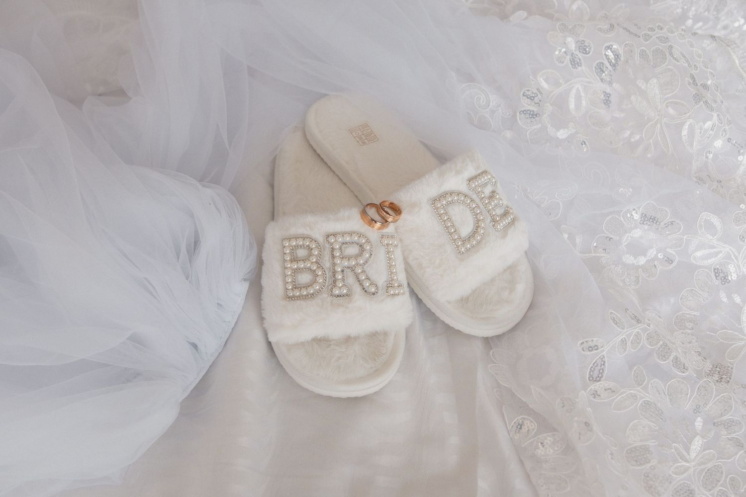 White wedding dress with delicate lace details and a flowing veil laid out on display.