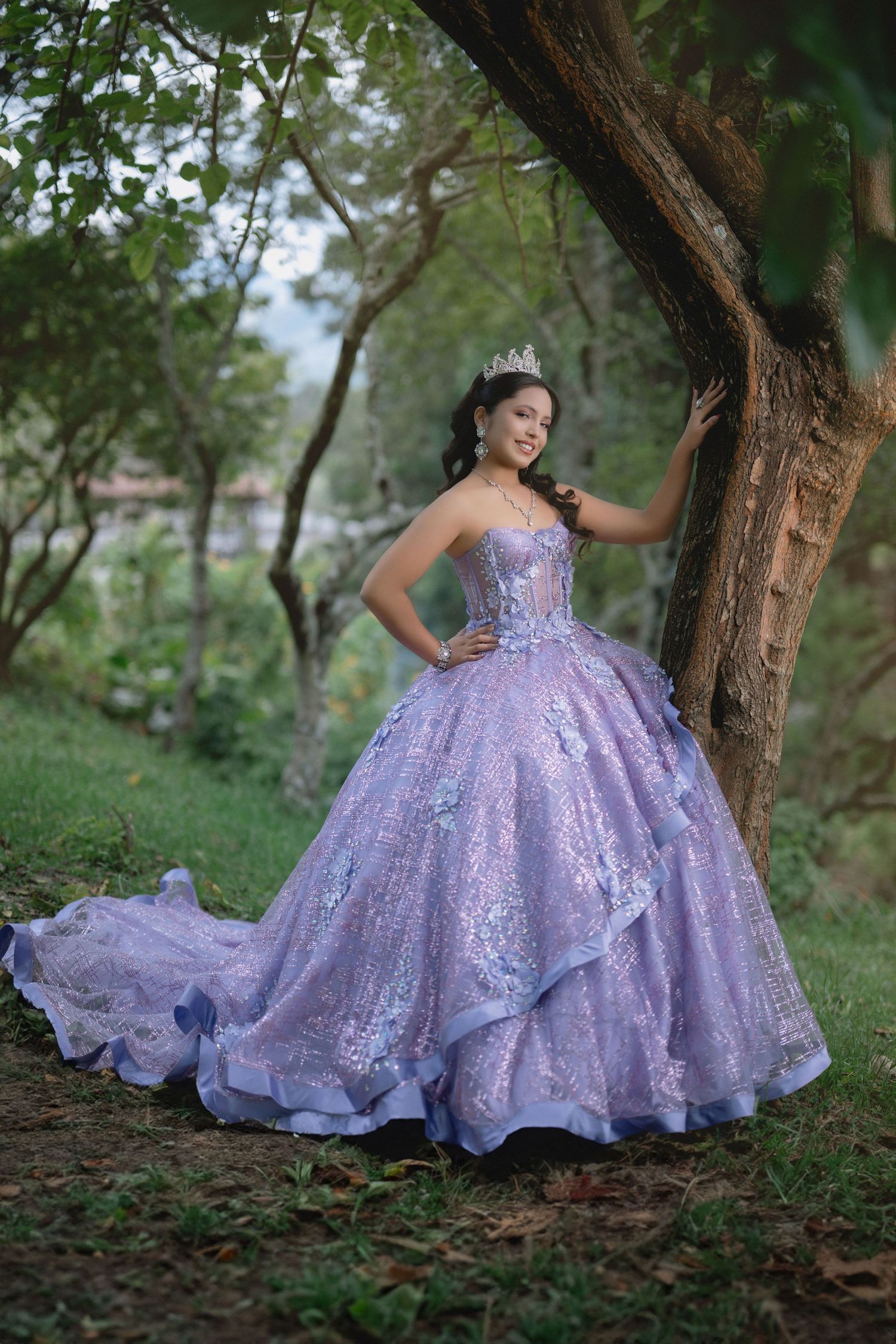 A lavender glitter ball gown with a sweetheart neckline sparkles in an outdoor woodland setting during a photo session.