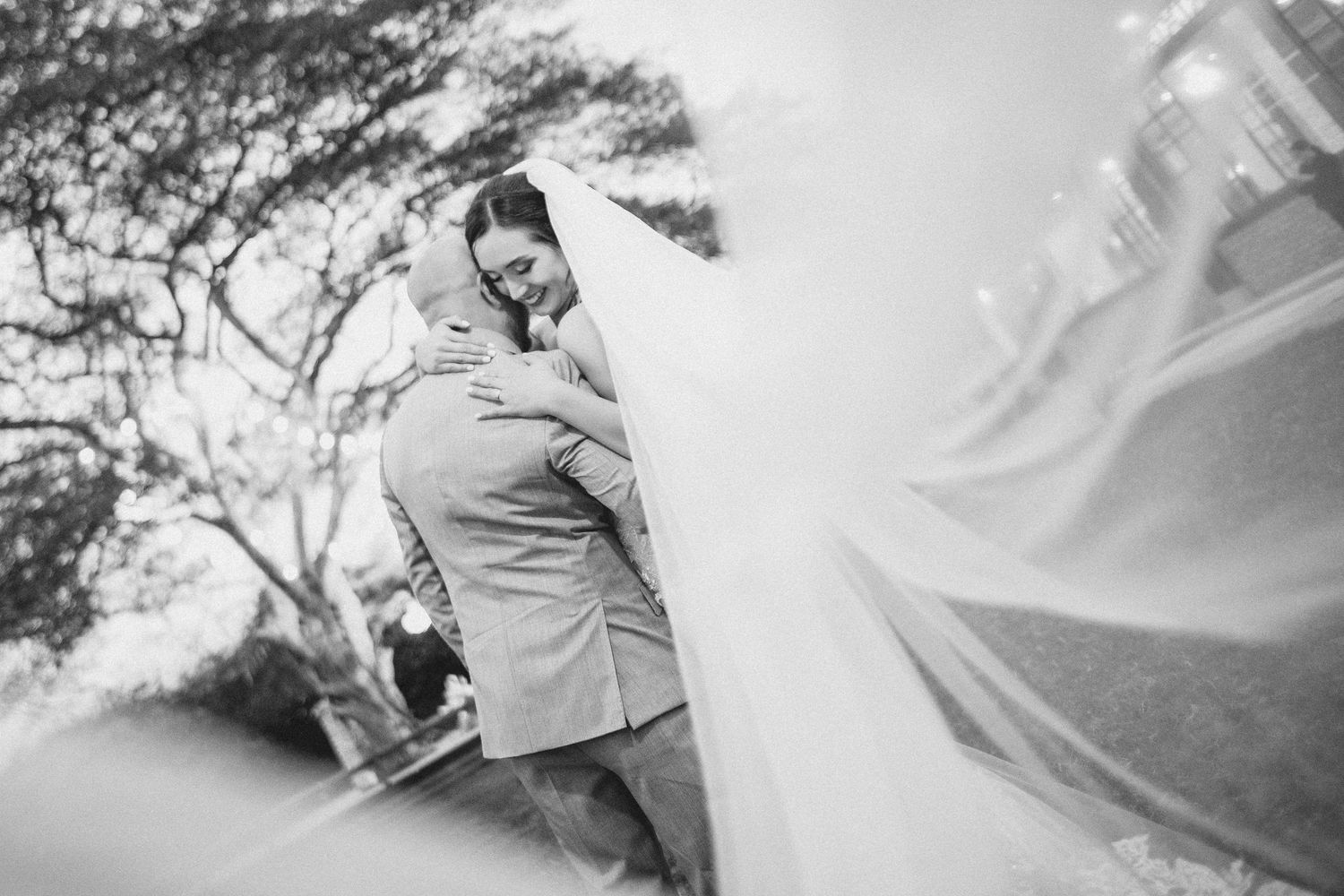 A couple embraces in a snowy winter forest setting during a romantic outdoor photoshoot.