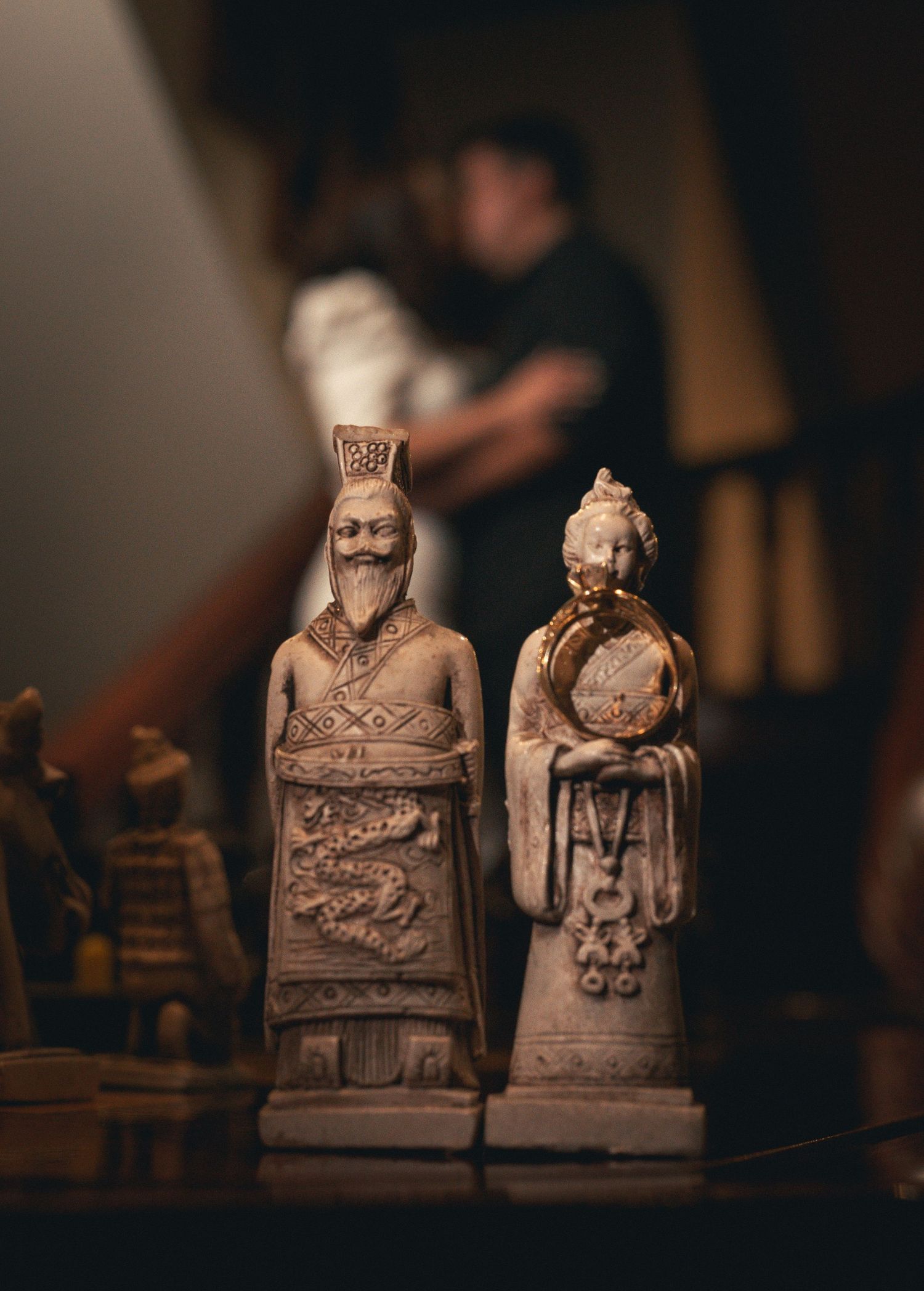 Vintage clay chess pieces with ornate royal figures displayed in moody lighting against dark background.