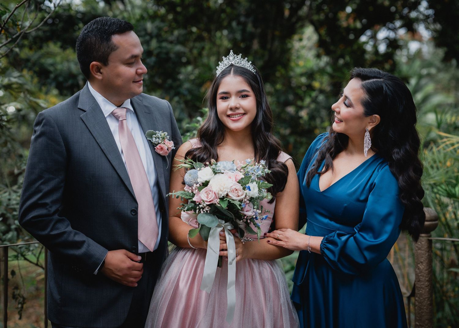 Wedding party in pink and navy blue attire poses together in an outdoor garden setting.