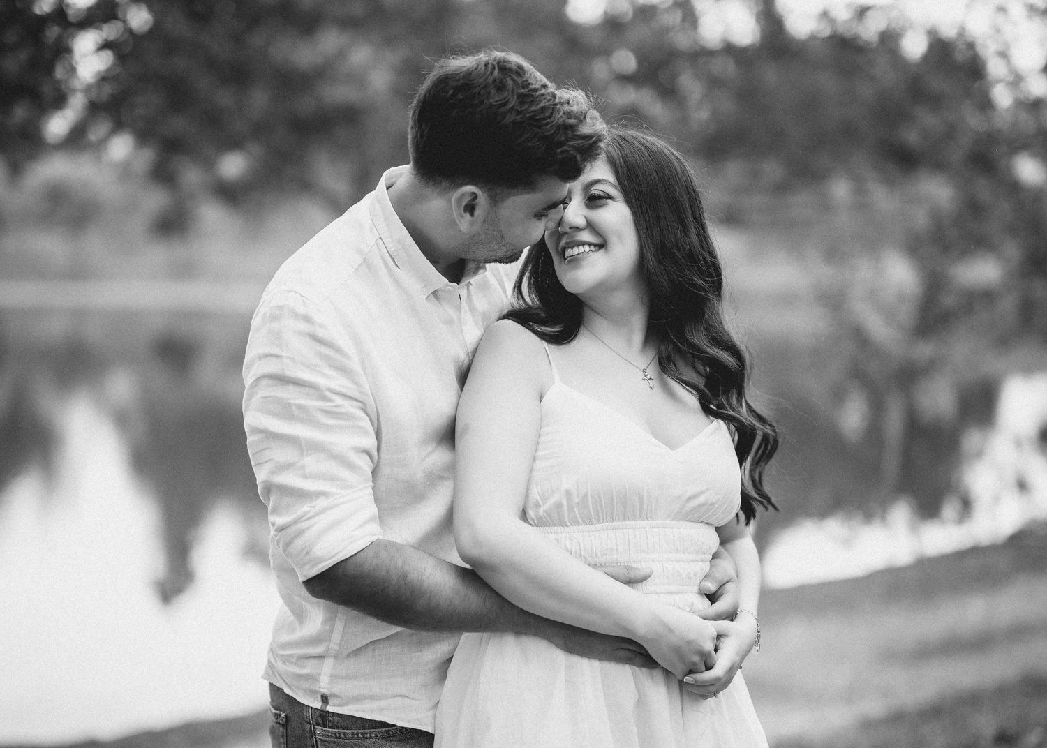 A romantic black and white photo series of a couple embracing outdoors in a park setting.