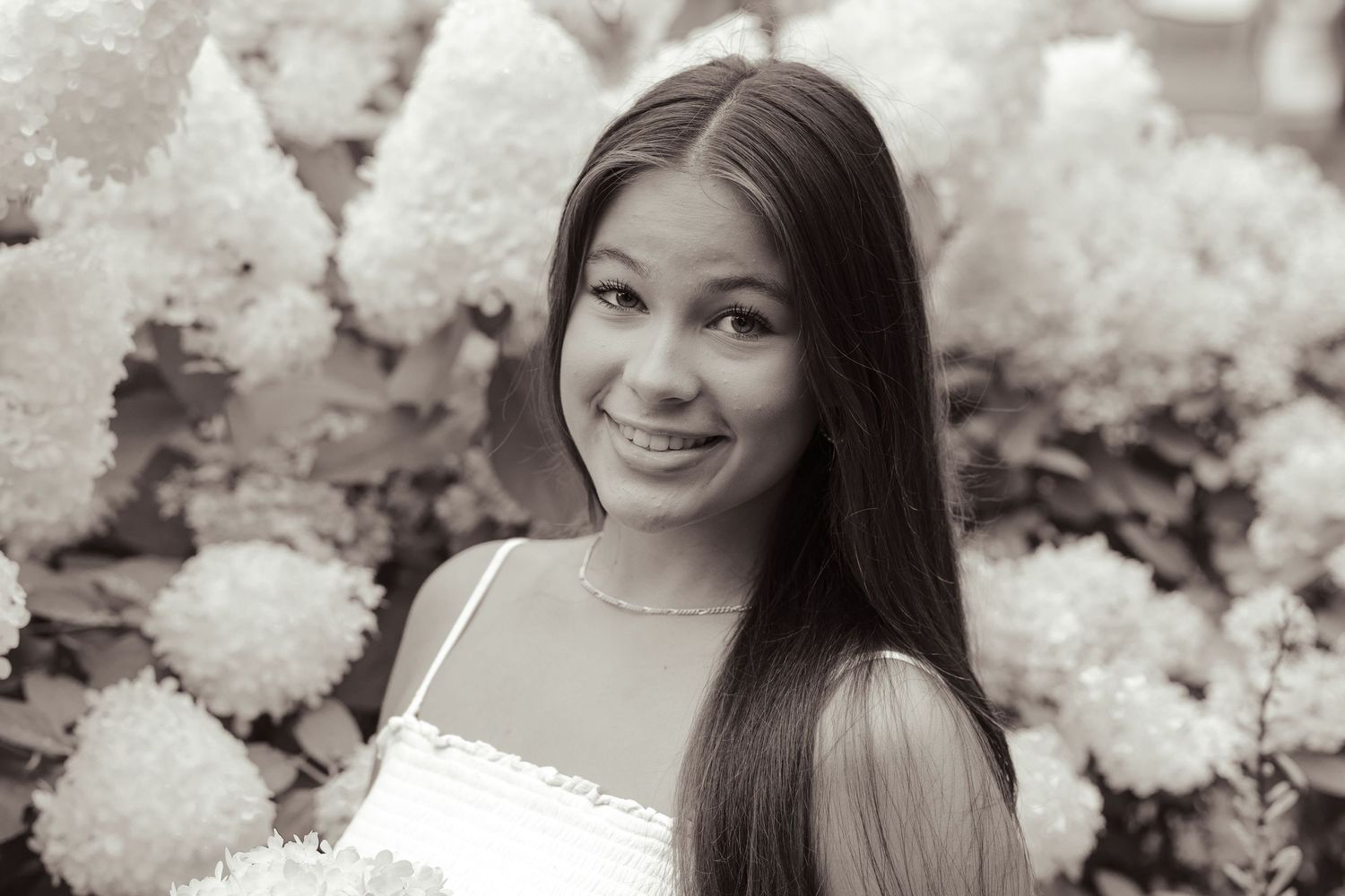 Portrait of a person in white dress against floral background.