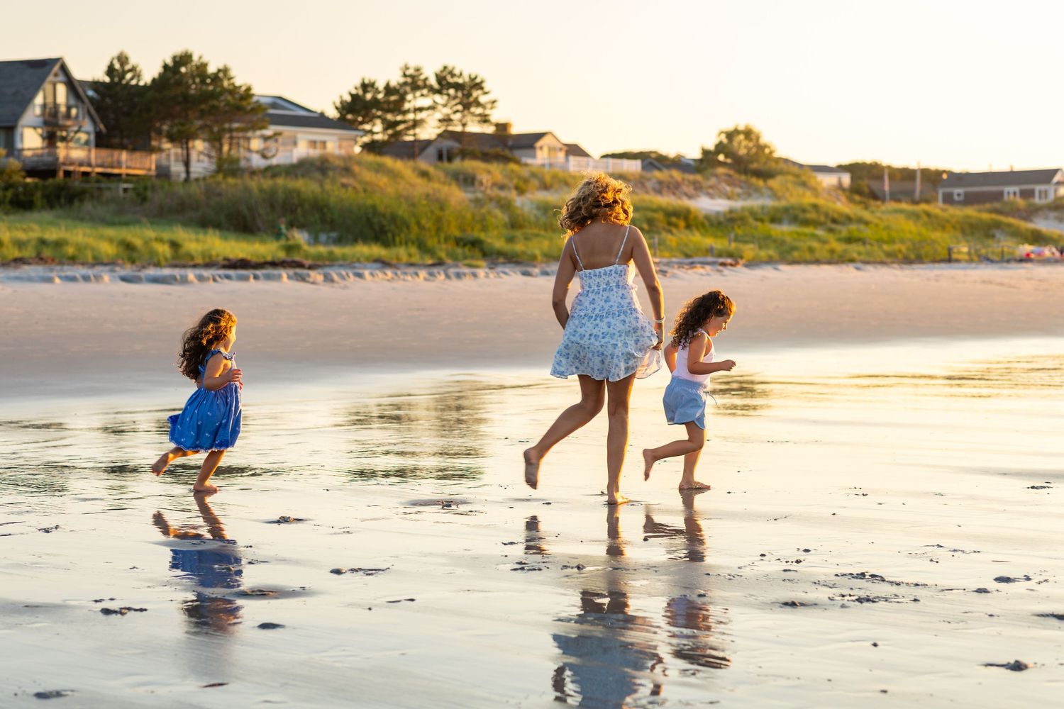People playing and walking along the beach shore during sunset.