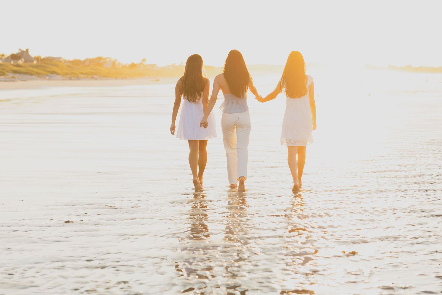 Silhouettes walking along a beach shoreline during golden sunset.
