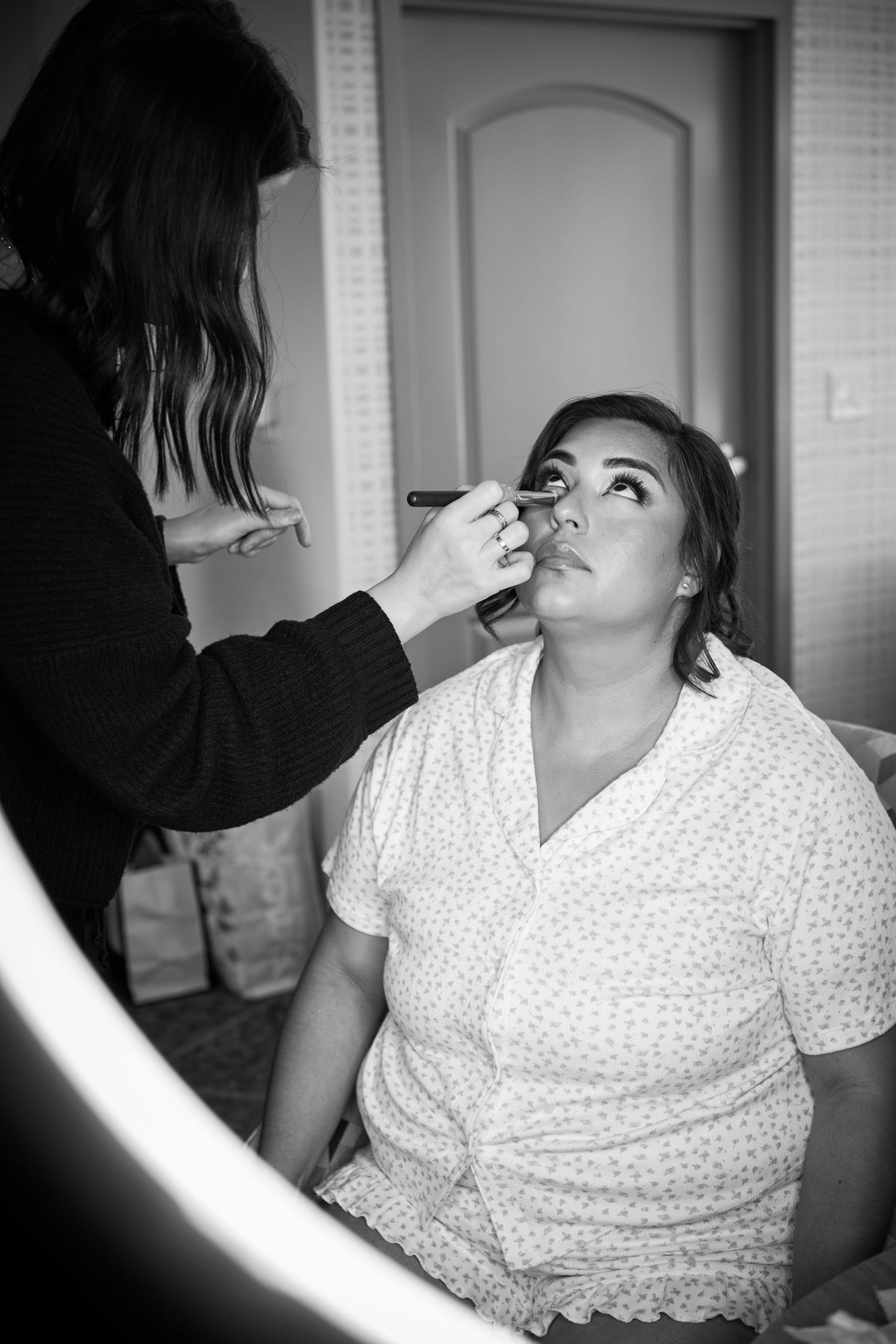 A getting ready scene with someone having makeup applied while wearing a polka dot robe.