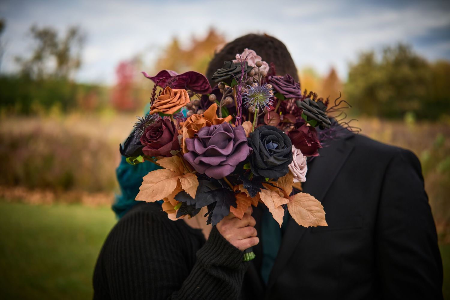 Wedding party members wearing dark suits with deep purple and burgundy floral boutonnieres.