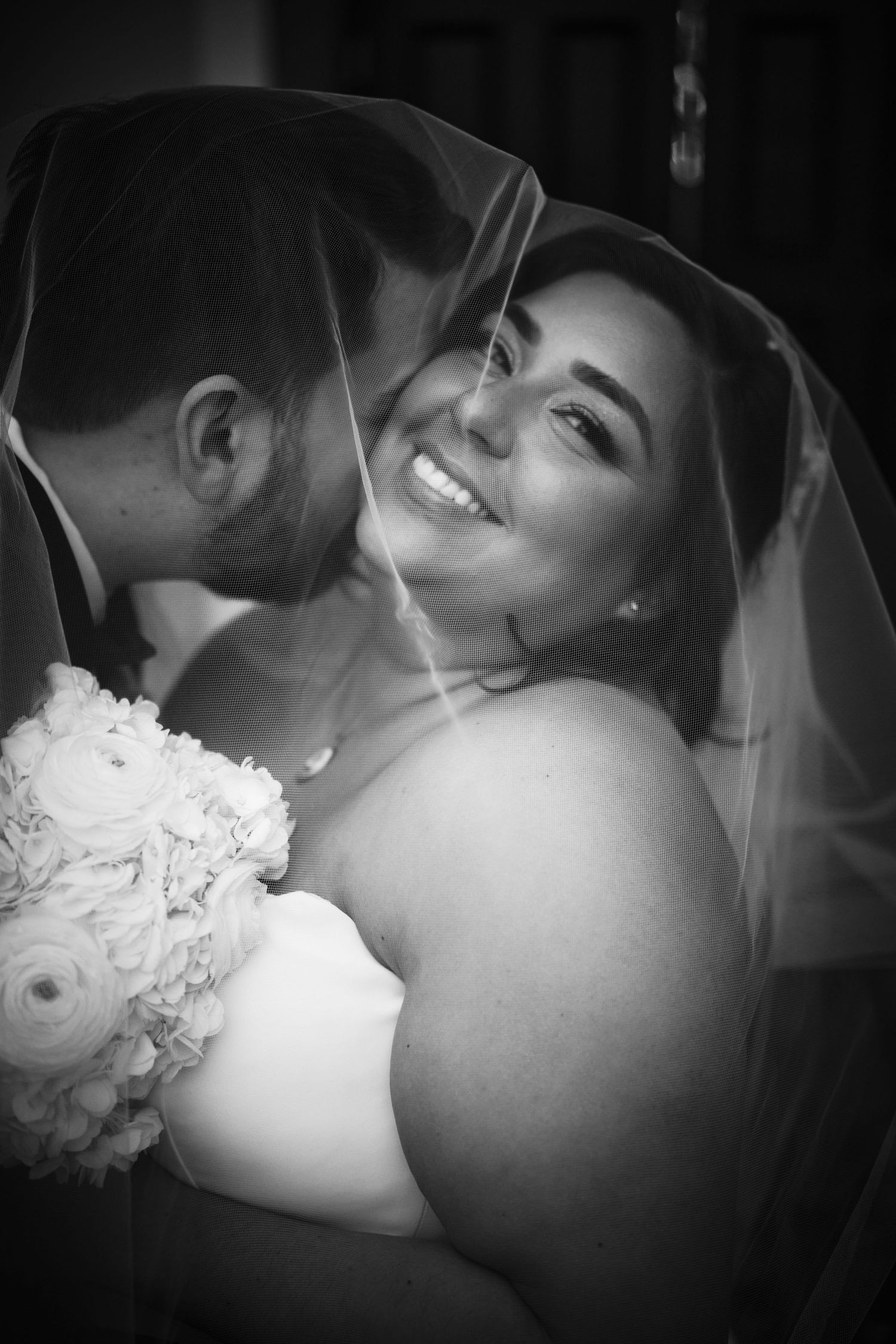 An intimate black and white wedding portrait through a veil.