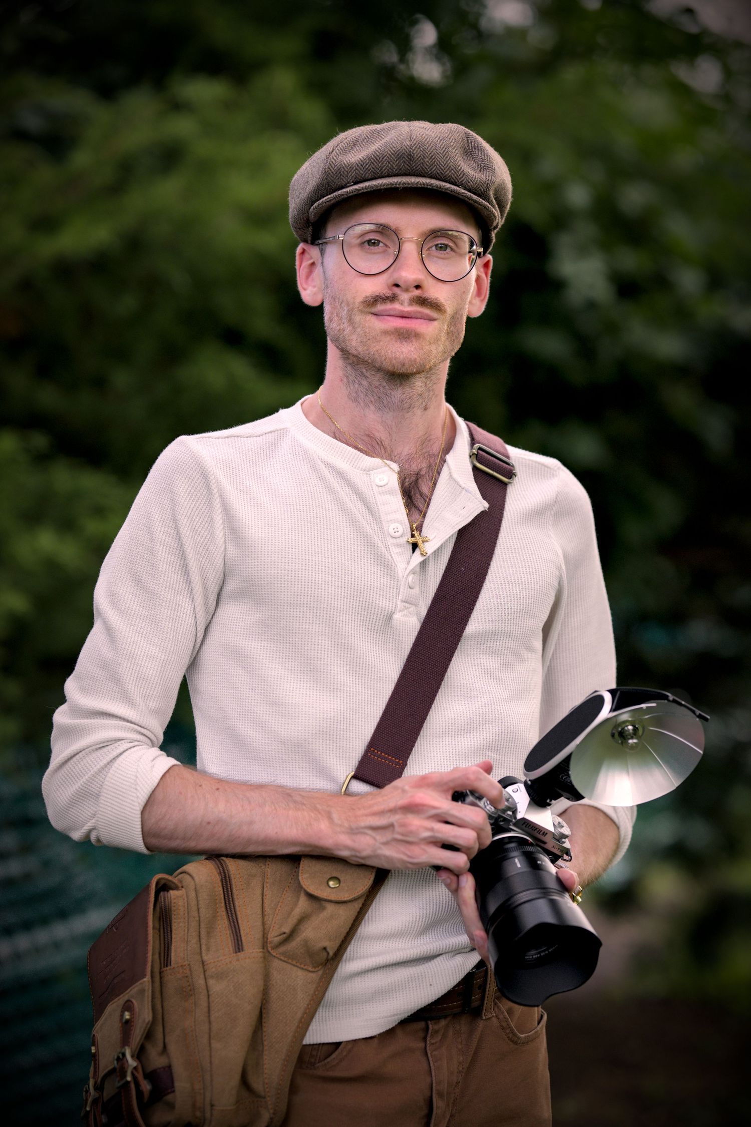 Photographer in vintage attire with newsboy cap and suspenders holding a camera in multiple poses.
