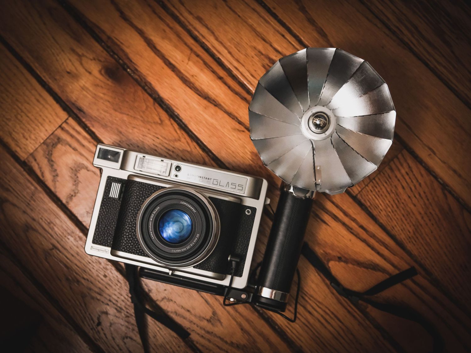 Vintage camera with flash bulb attachment on wooden surface.