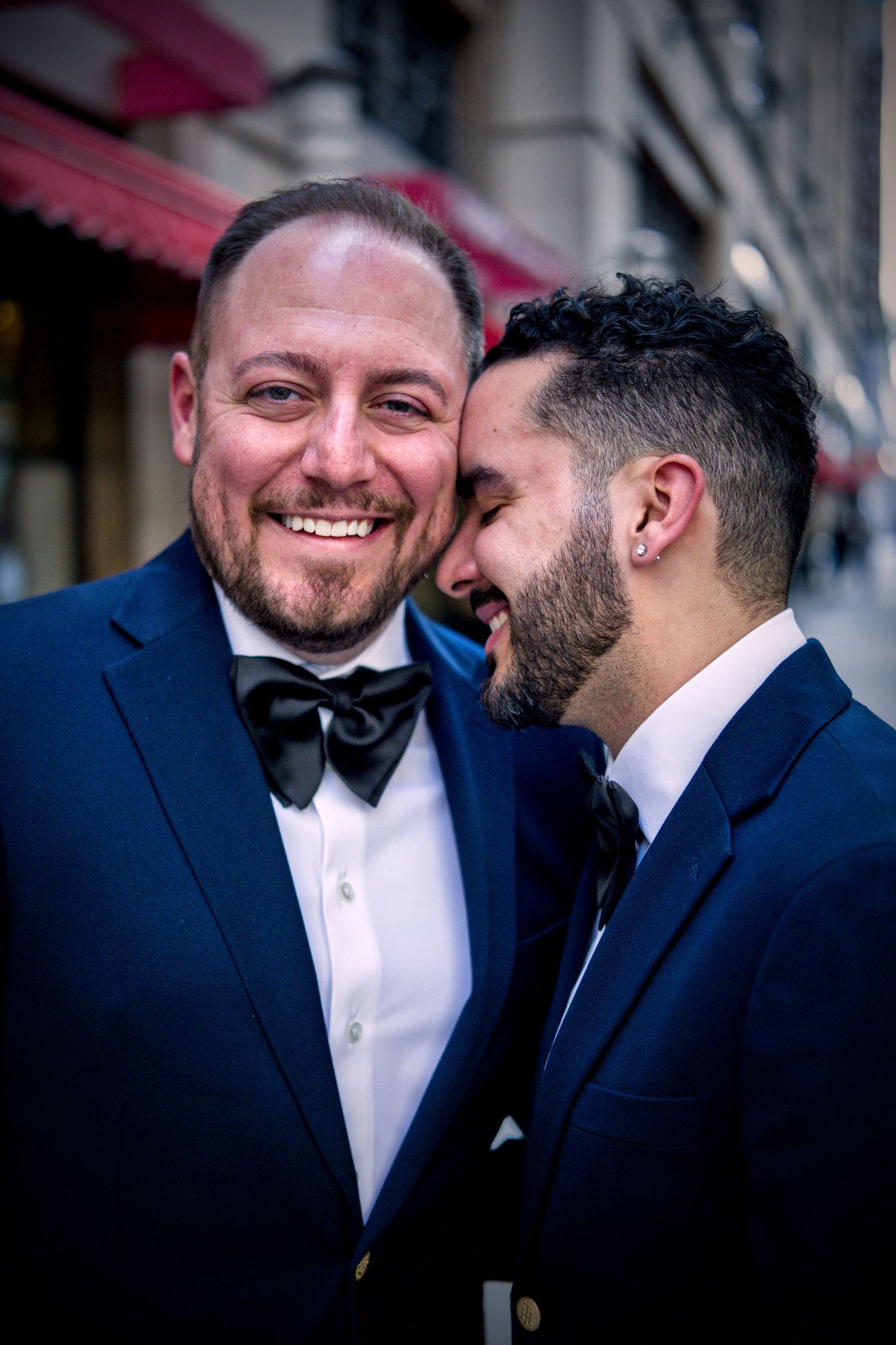 Two people in formal attire sharing intimate moments and laughter during wedding portraits.
