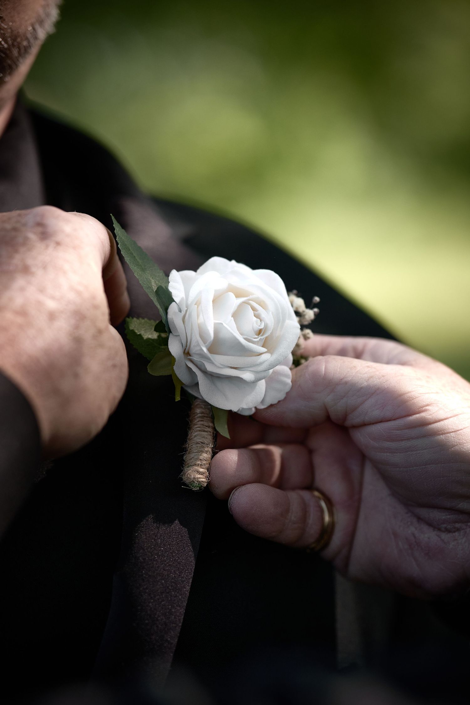 Close-up sequence of white rose boutonniere being pinned to lapel.