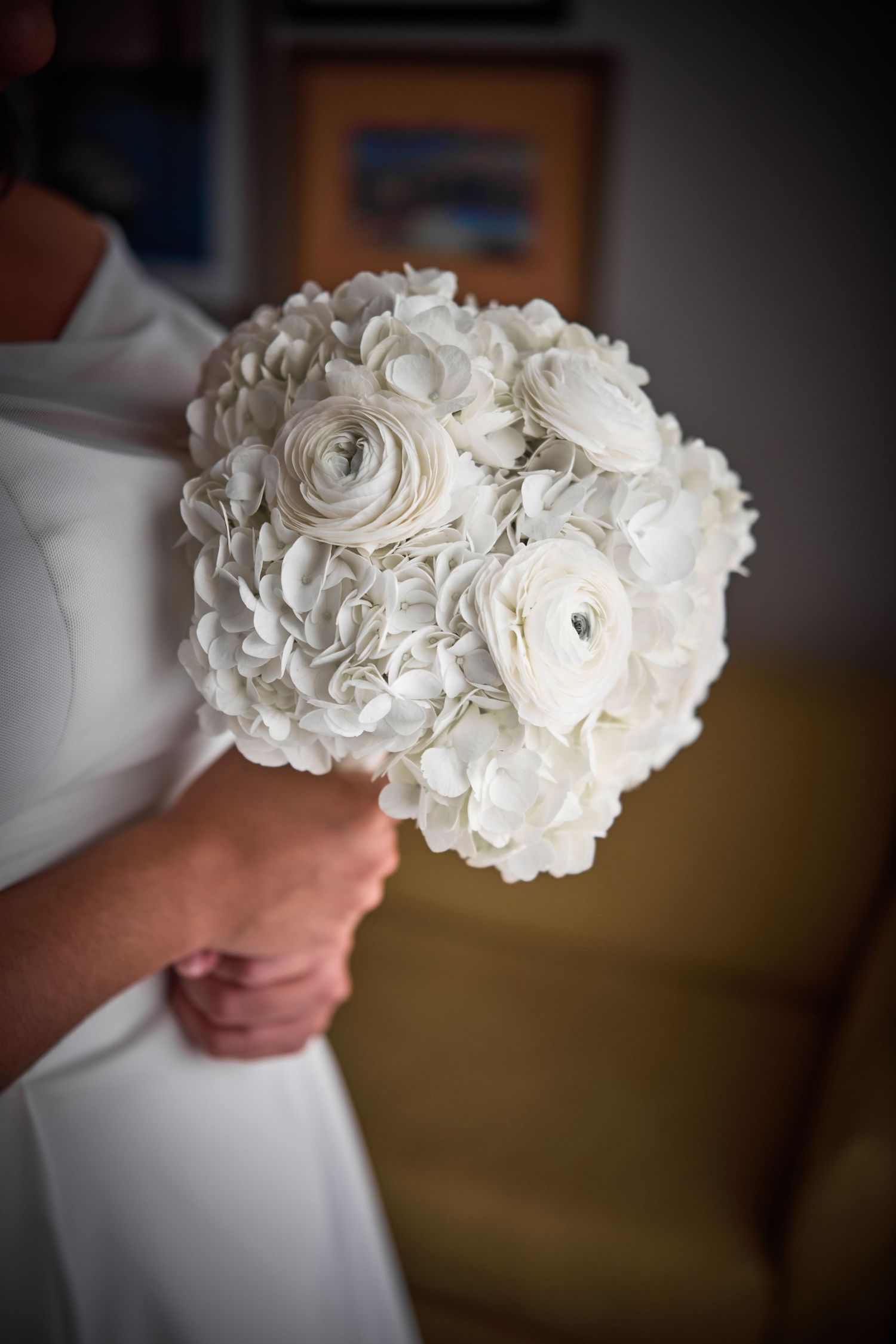 A delicate white rose wedding bouquet held against a light background.