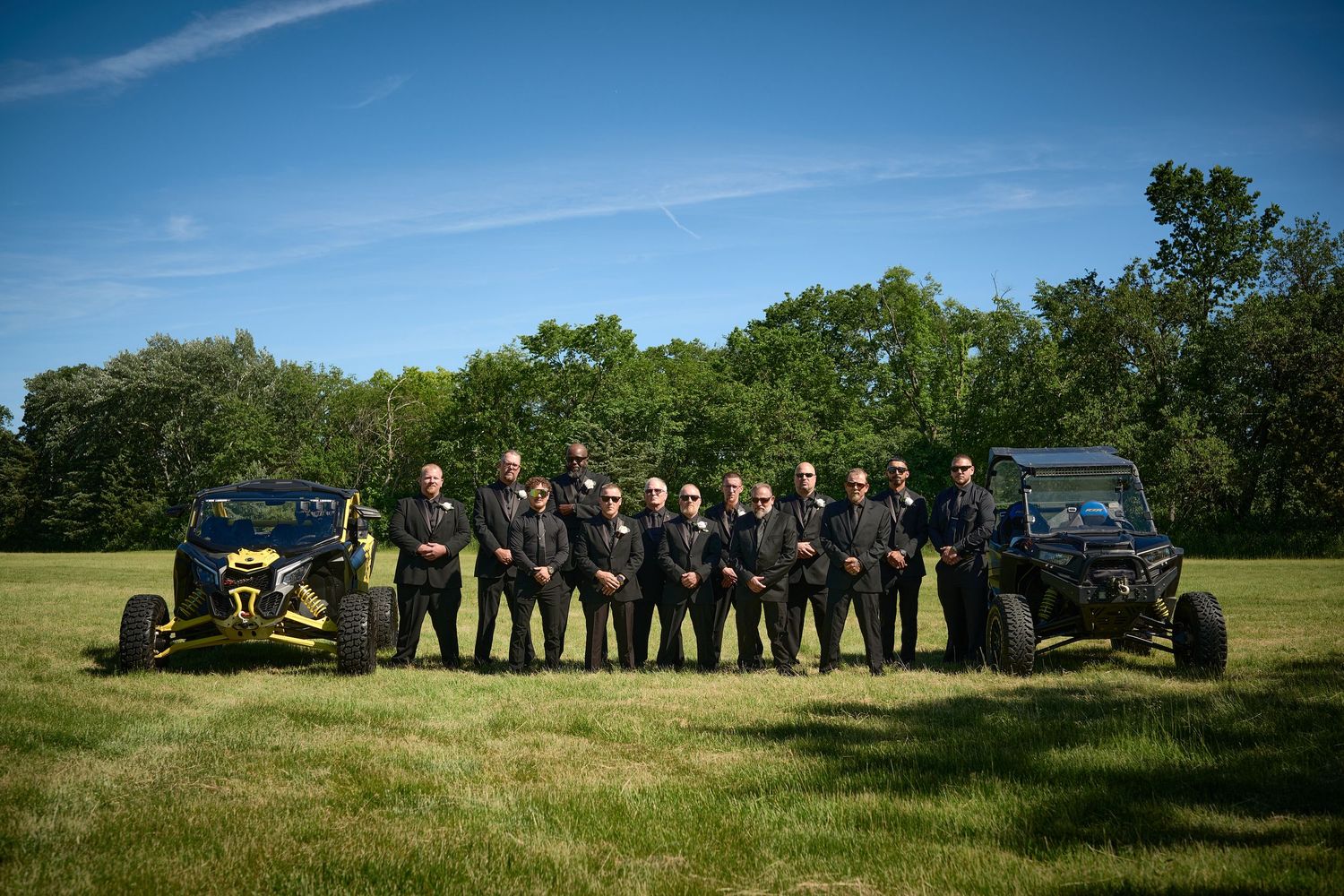 Wedding party lines up for panoramic photo shoot in scenic outdoor setting.