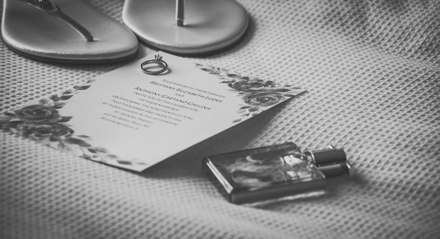 Wedding accessories including rings and shoes arranged on a textured surface.