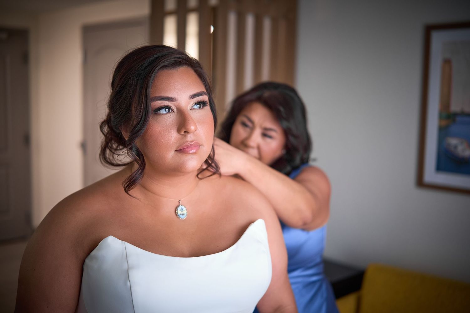 Candid getting ready moments showing wedding dress preparations in natural light.