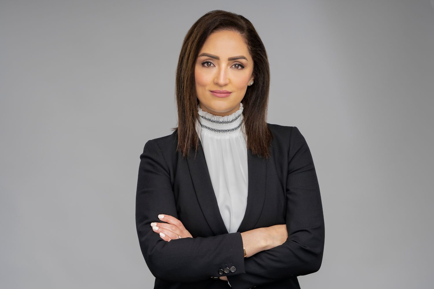 Corporate portrait of a person in black blazer and turtleneck with arms crossed.