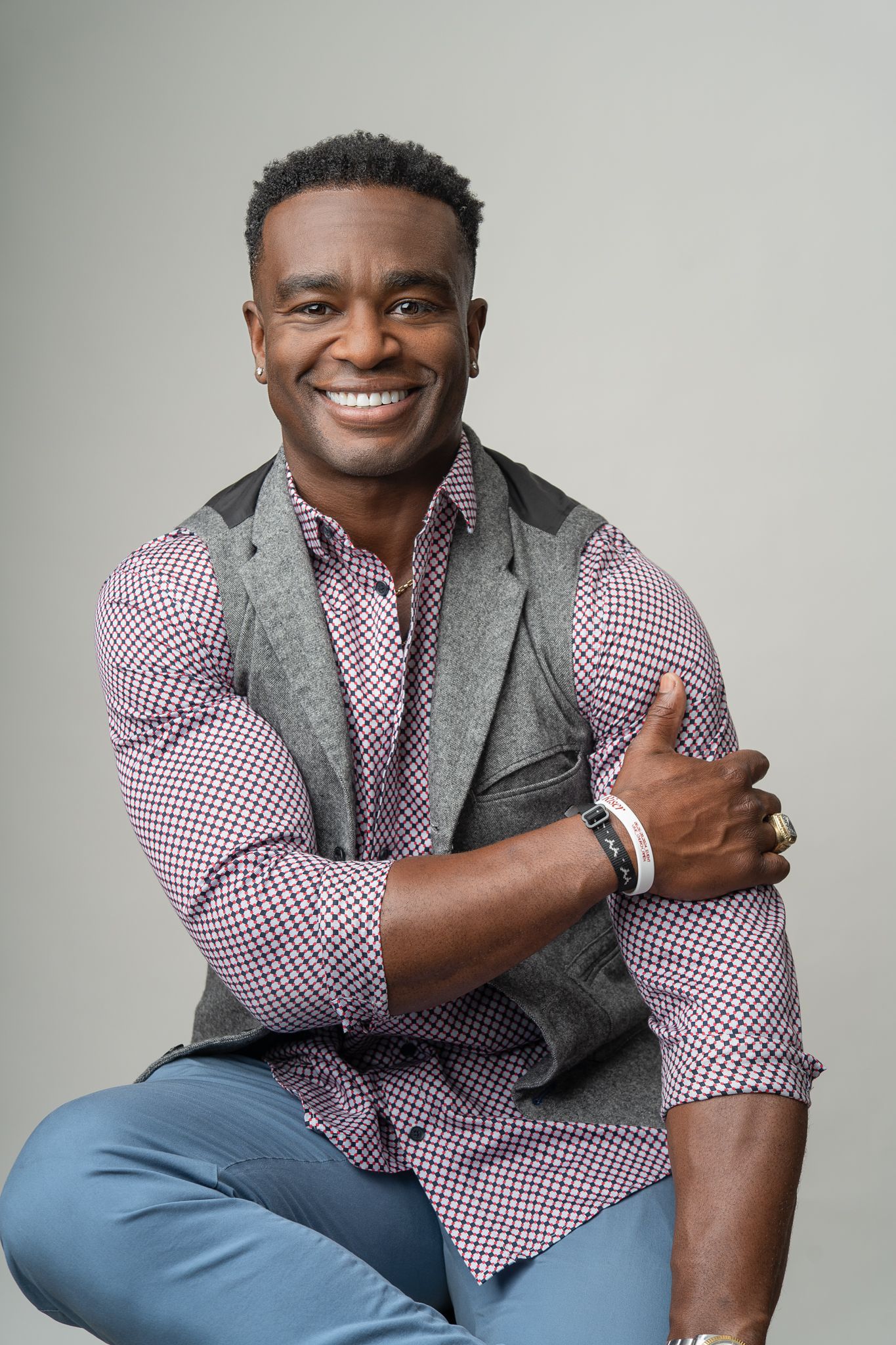Professional portrait series showing a man in a checkered burgundy shirt and grey vest posing against a light background.