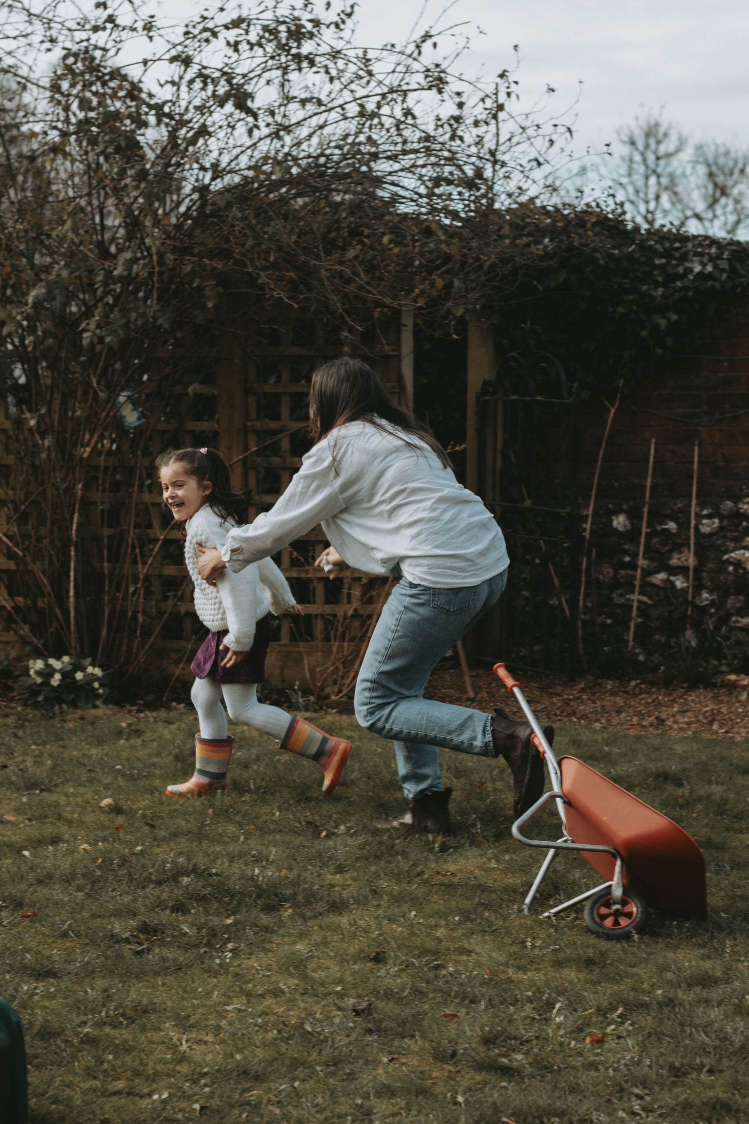 A playful chase scene in a backyard garden with outdoor furniture visible.