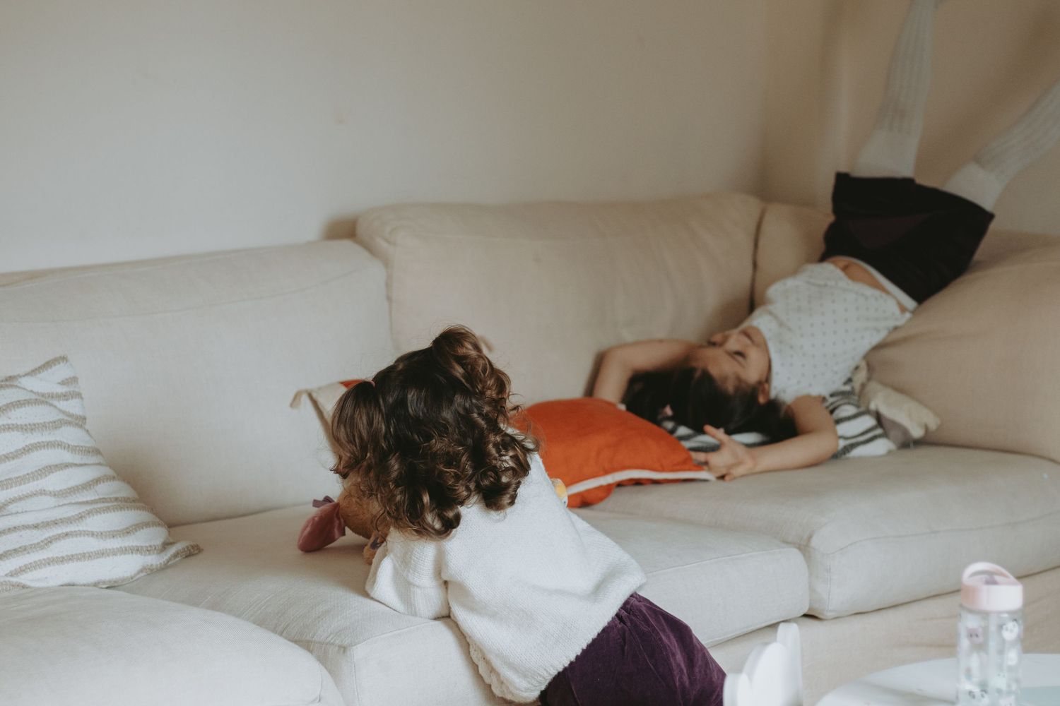 Children playing and relaxing on a white couch in a bright room.