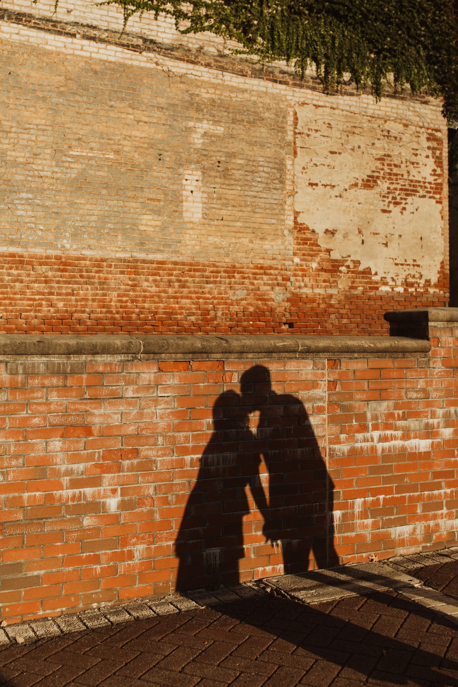 Silhouette of a loving couple's shadows cast on vintage brick wall in warm sunlight.