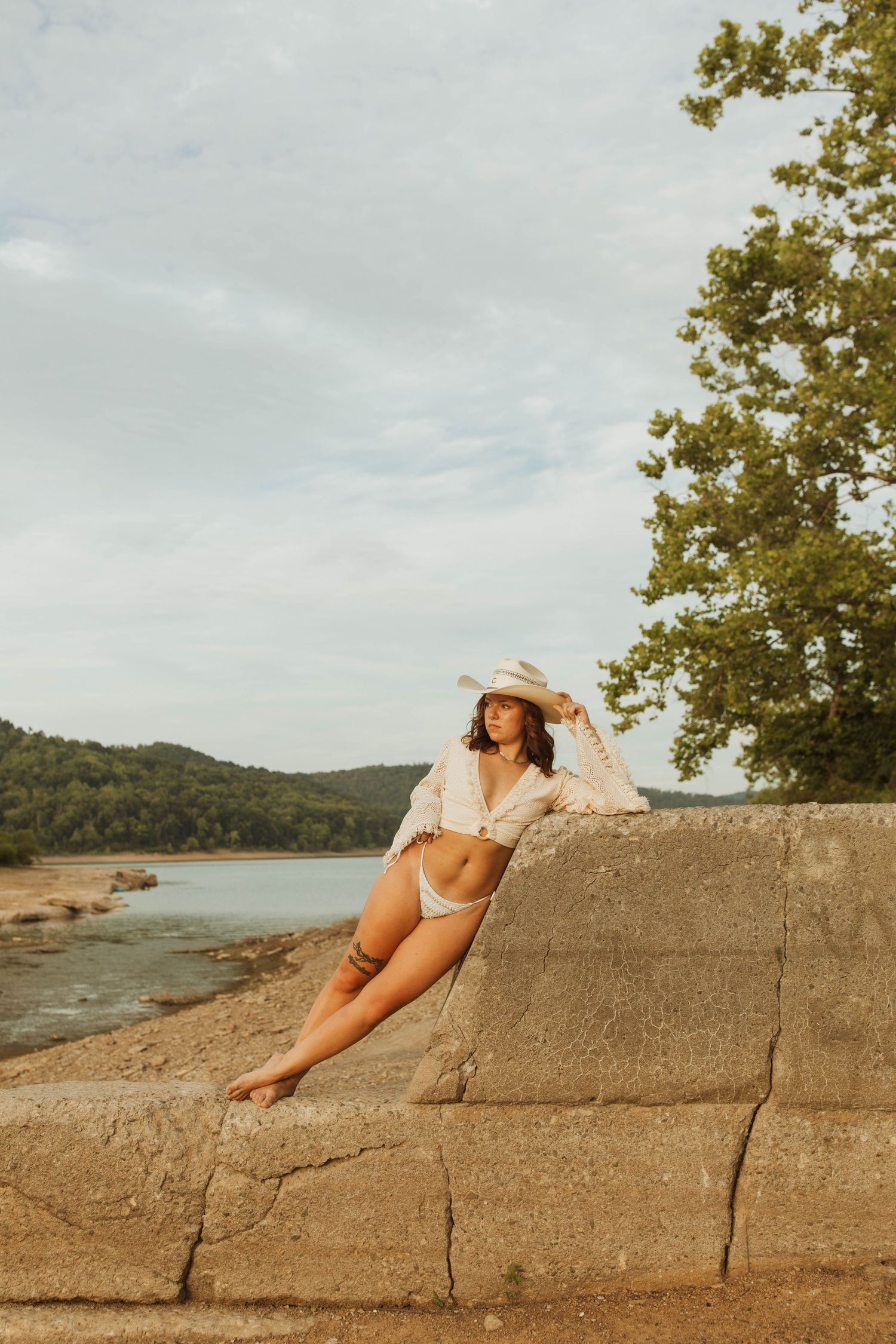 A relaxed summer scene with someone lounging on large rocks by a peaceful lake.
