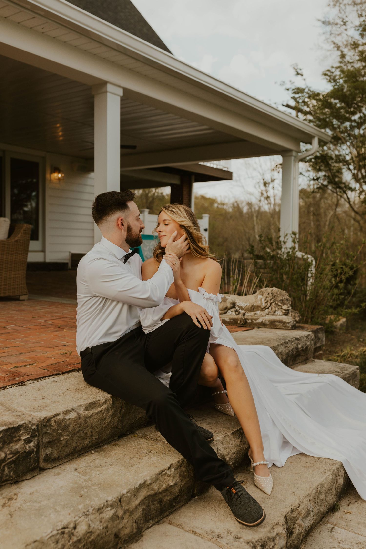A tender moment shared between newlyweds sitting on stone steps of a porch.