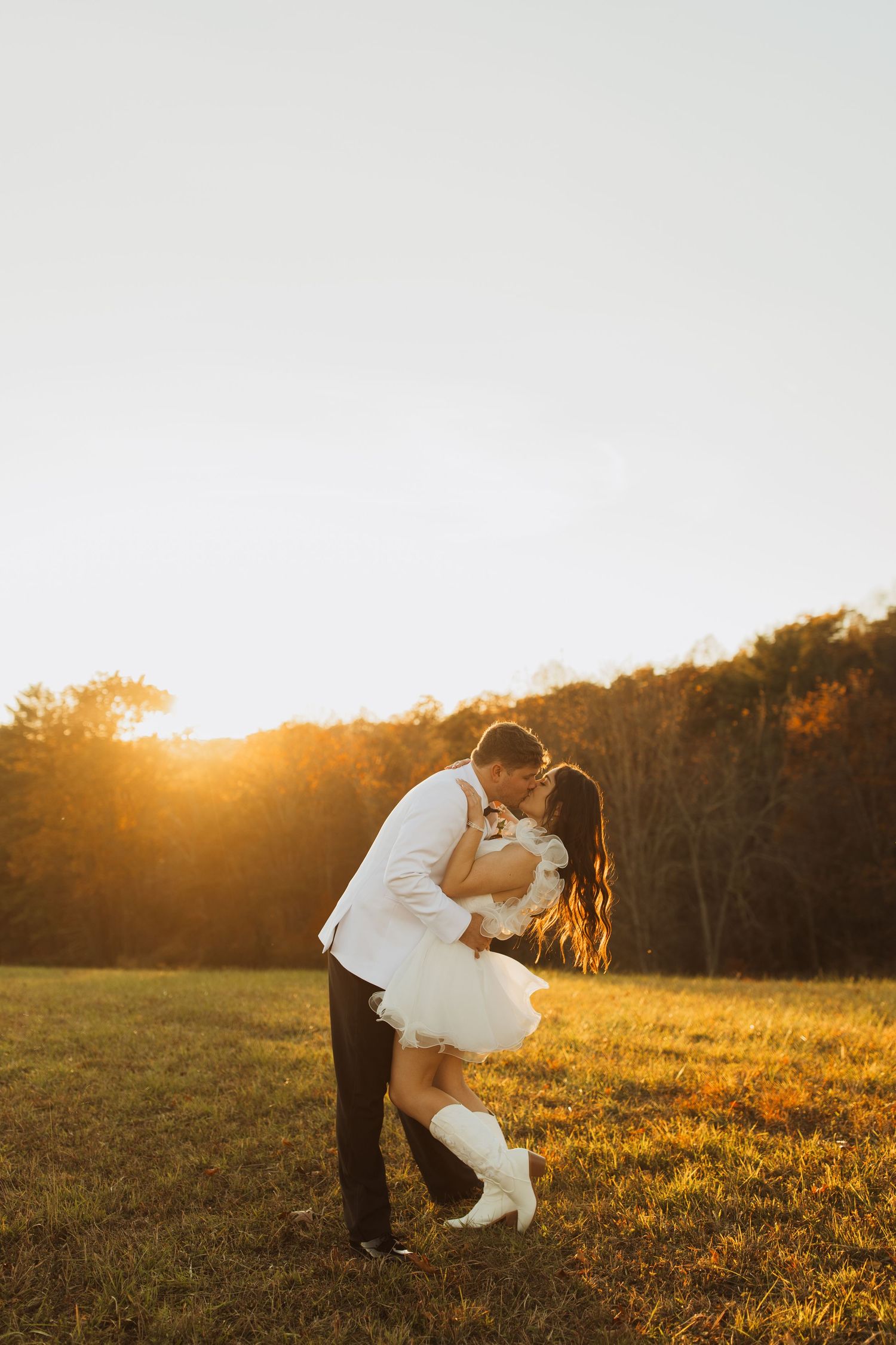 Romantic sunset portrait in a golden field with couple in wedding attire.