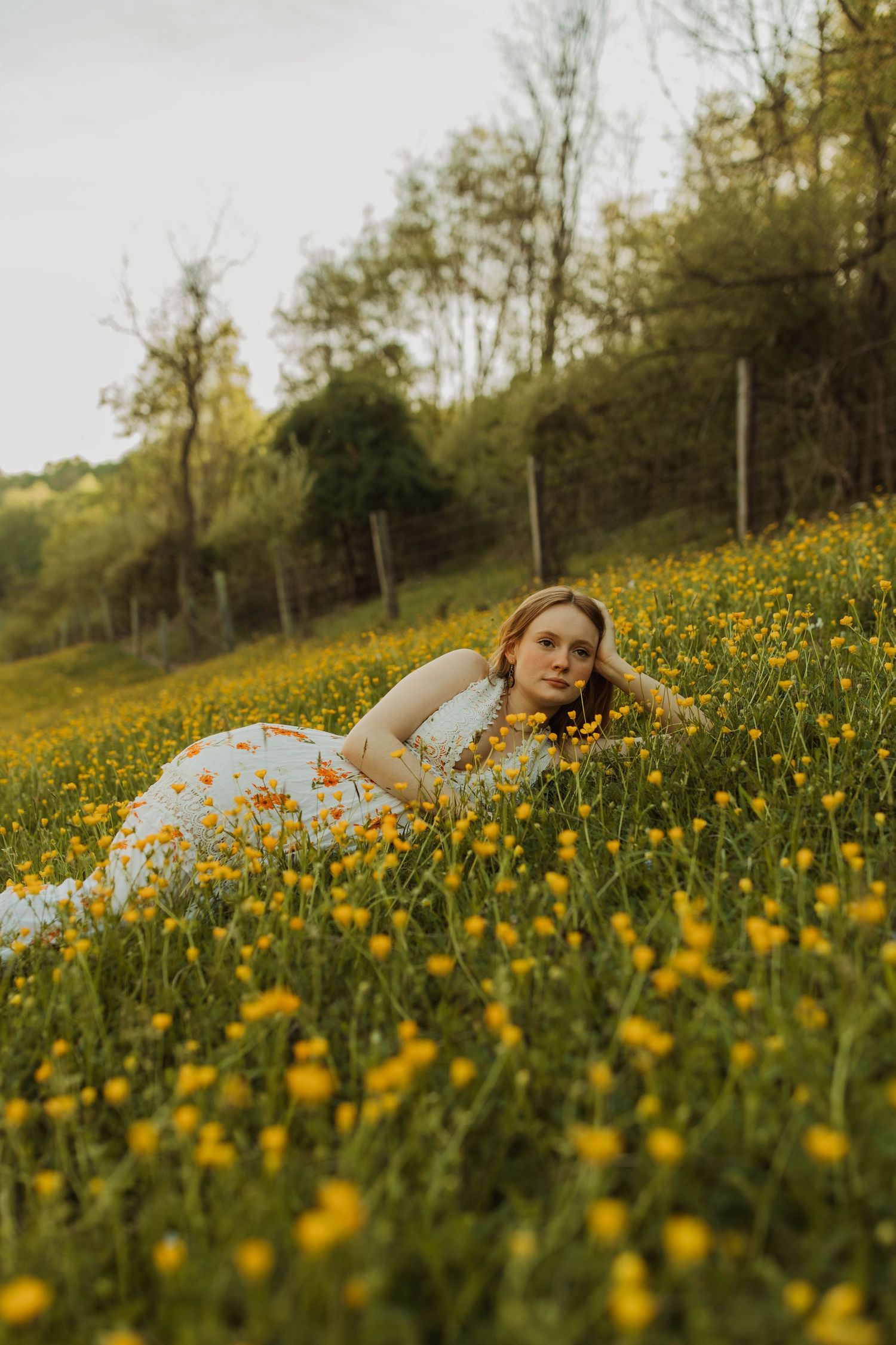 Romantic portrait in a field of wild yellow flowers wearing a white dress.