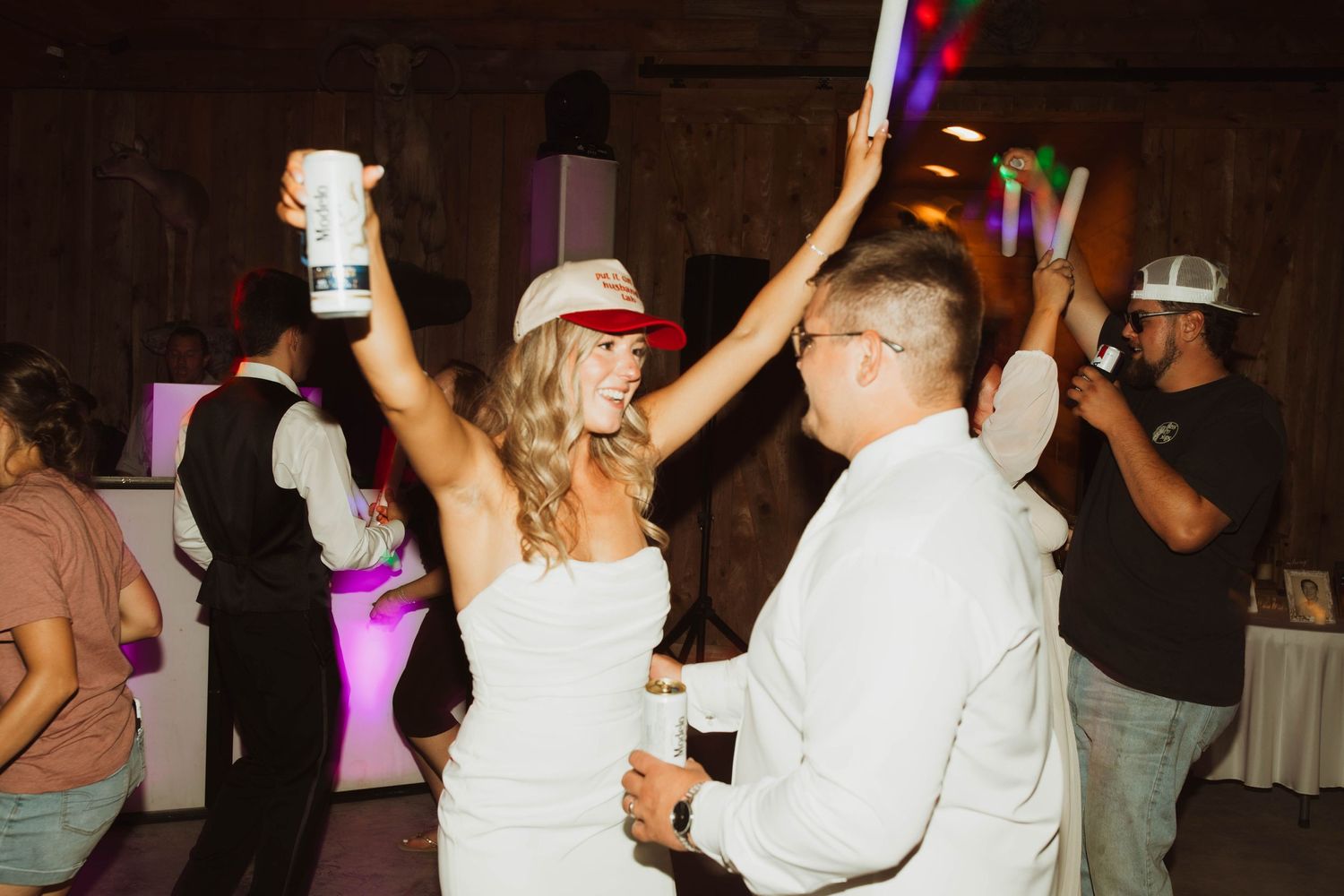Wedding celebration on a dance floor with glow sticks and party lights.