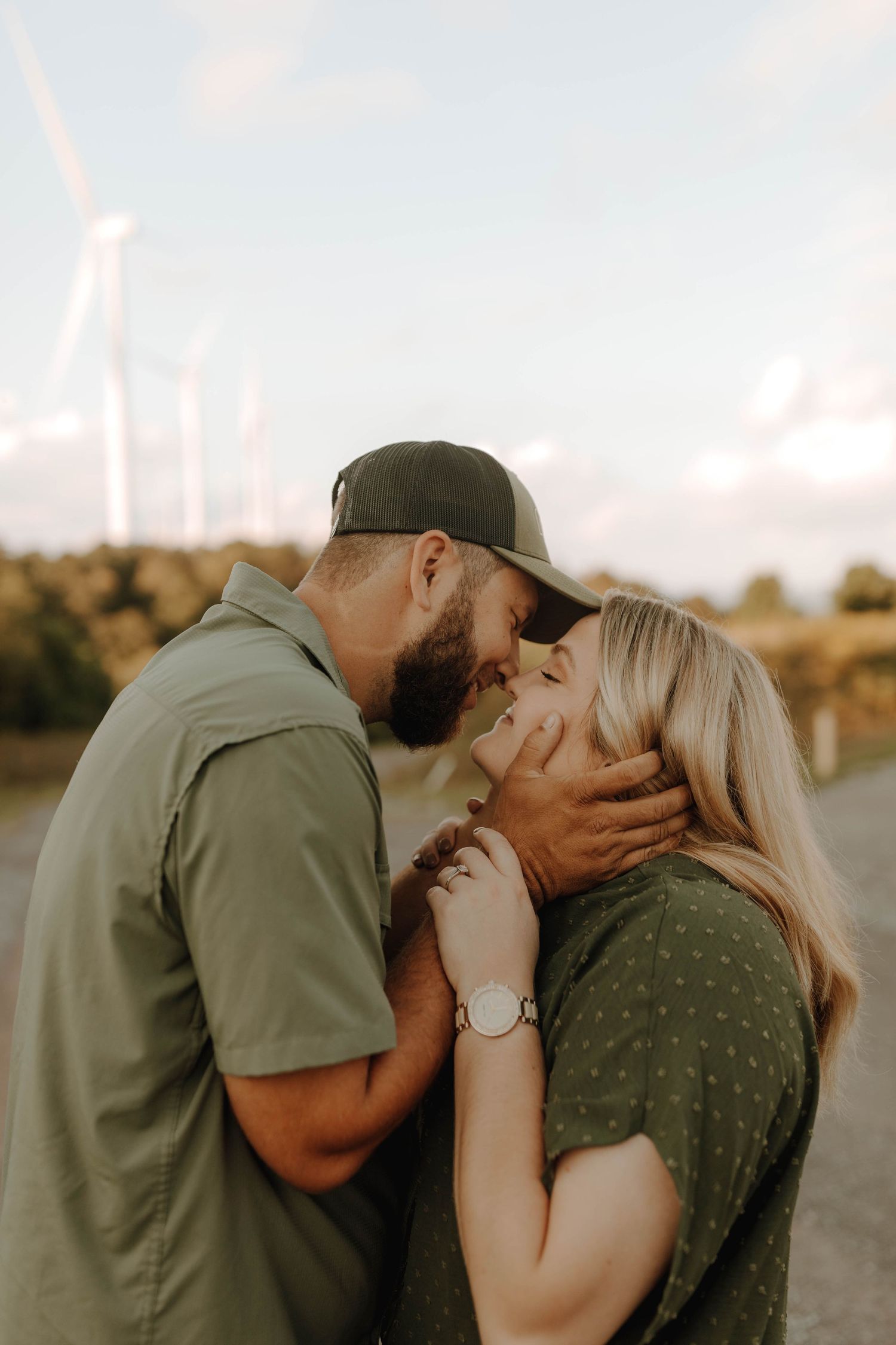 Tender moment between a couple with wind turbines visible in background.