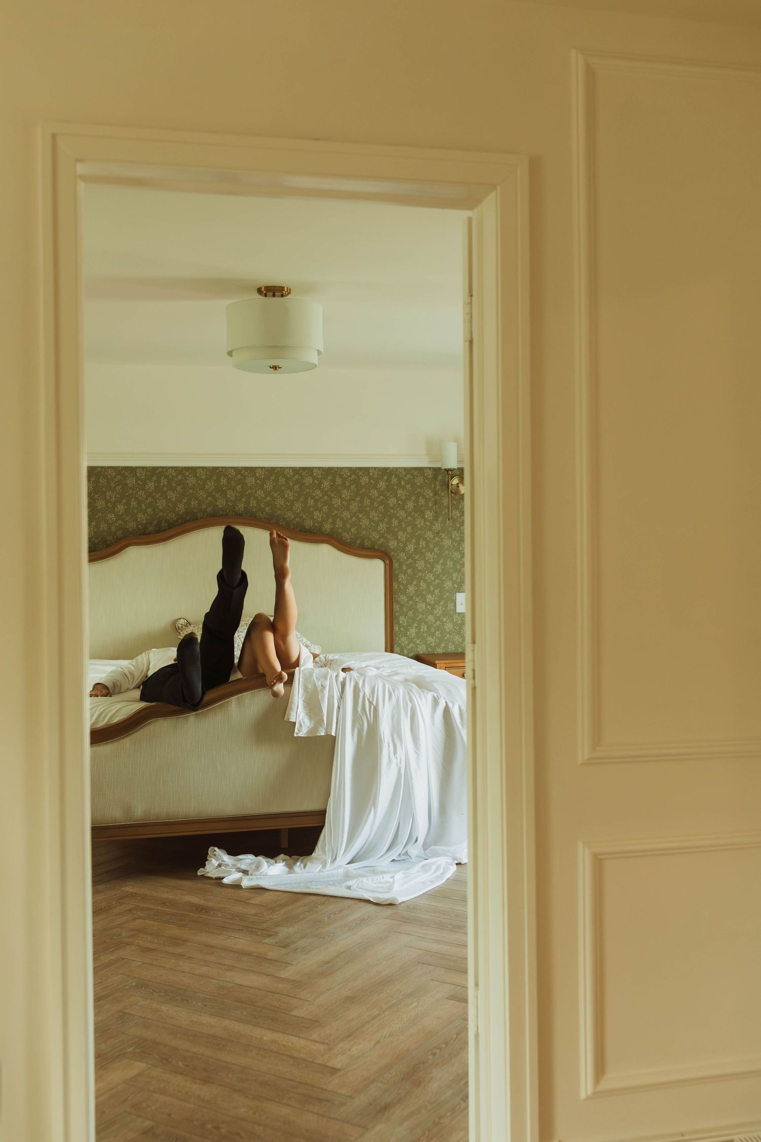 An artistic wedding photo framed through a doorway showing flowing white fabric.