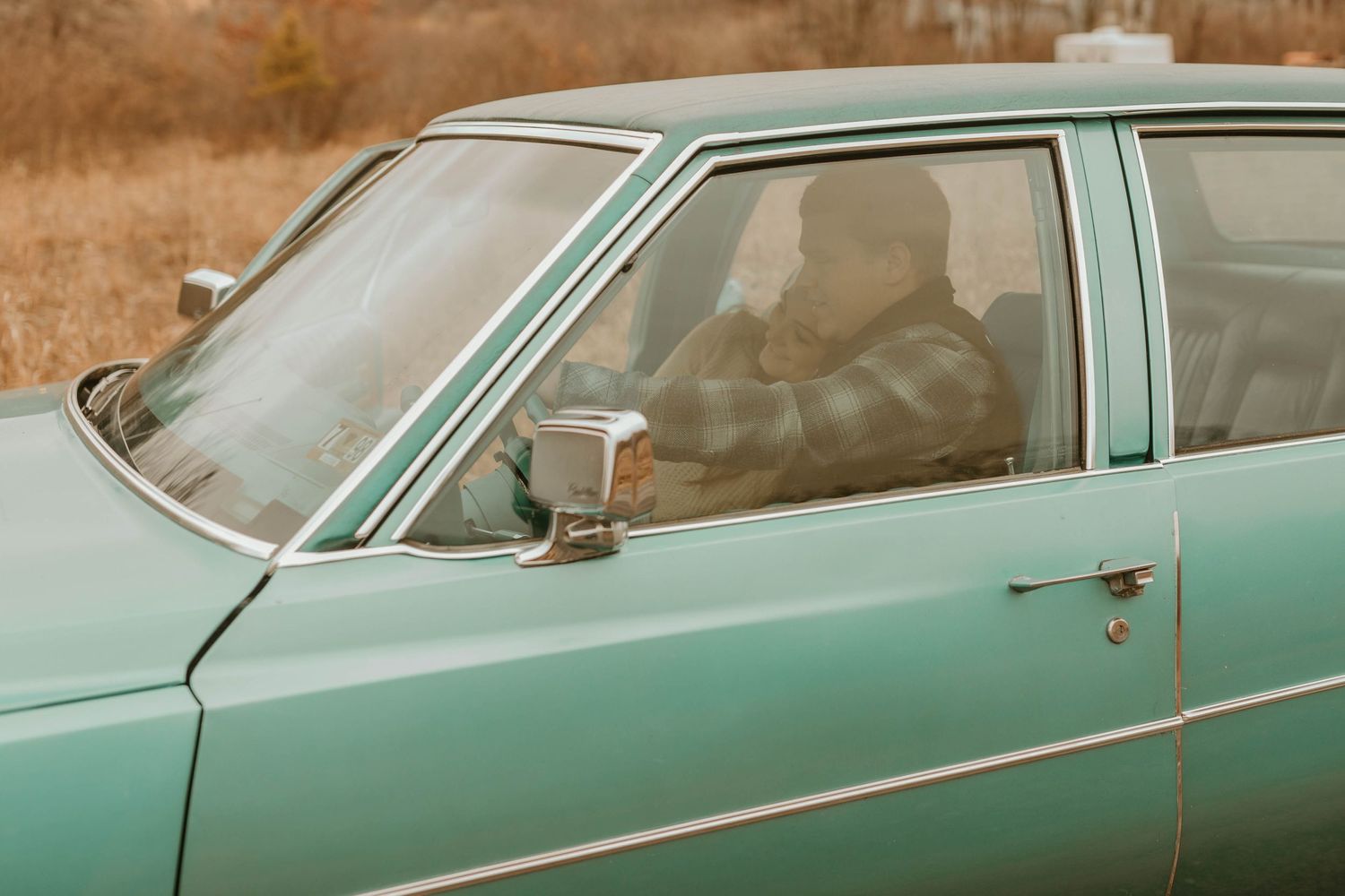 View through the driver's side window of a mint green vintage car.
