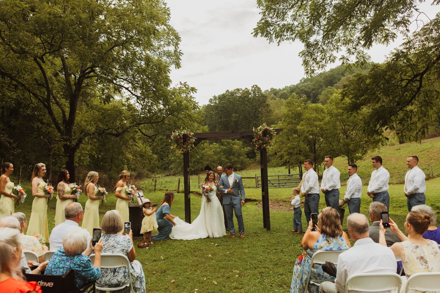 Outdoor wedding ceremony setup with white chairs and floral decorations in a natural park setting.
