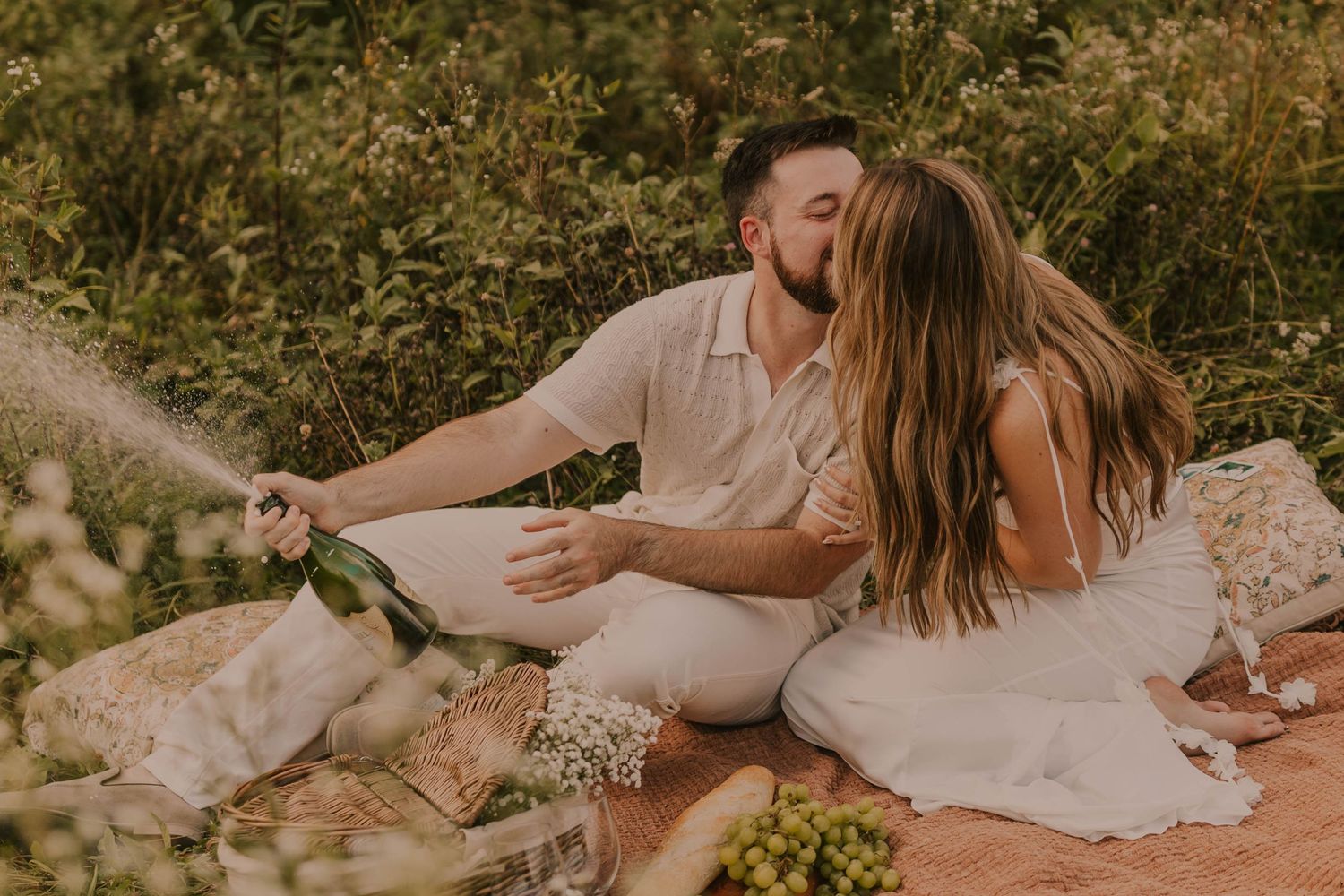 A romantic picnic scene with wine and flowers set against a natural outdoor backdrop.