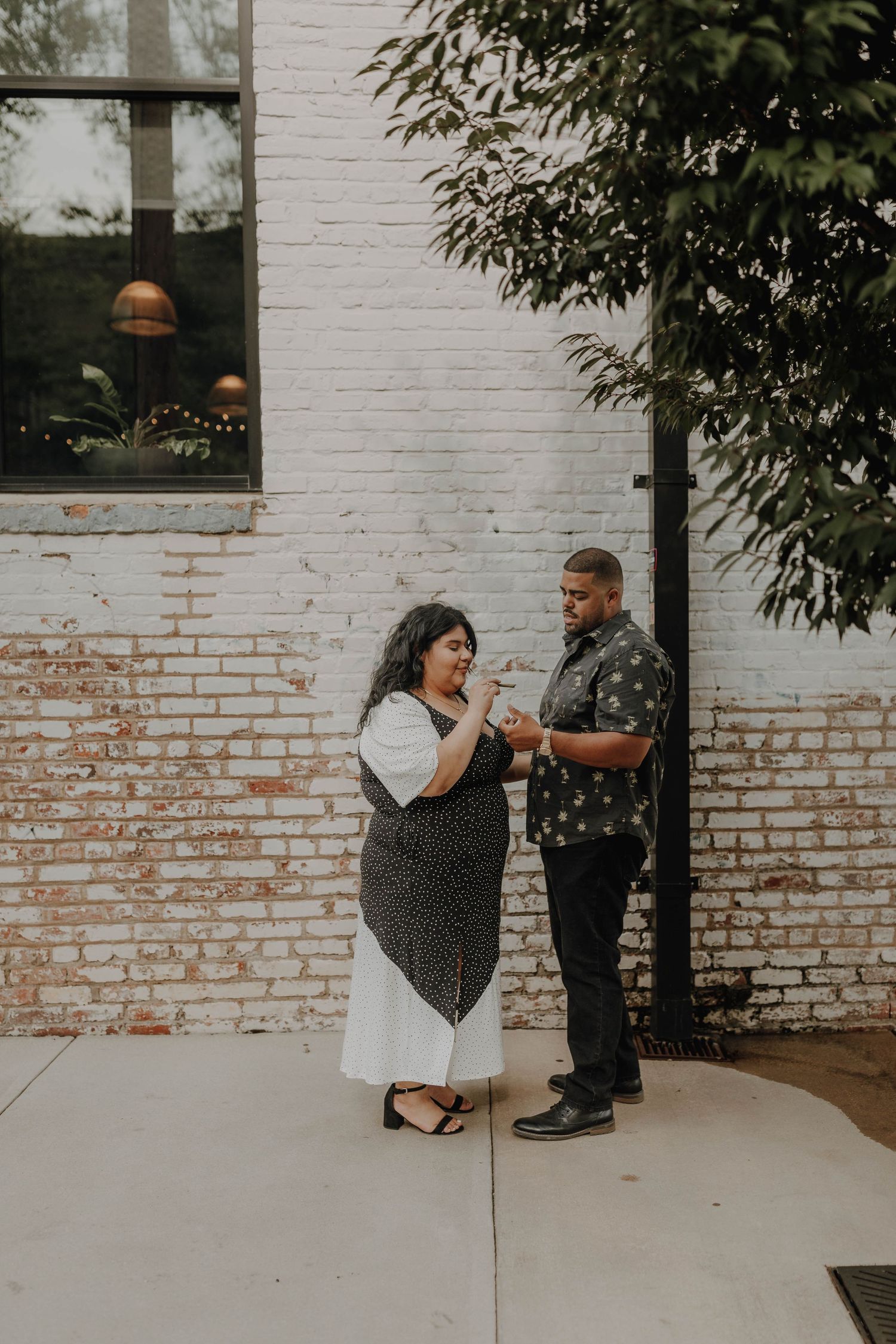 Couple sharing a joyful moment outside a white brick building.