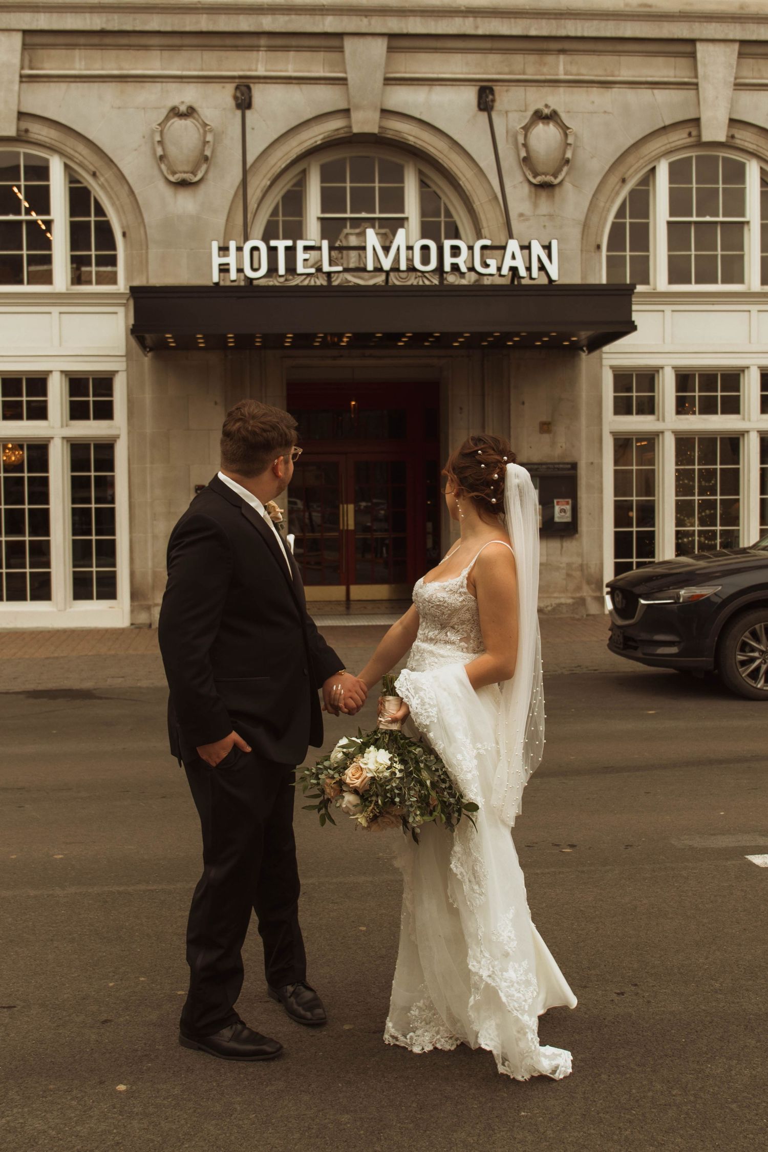 Wedding couple pauses for a photo beneath the Hotel Morgan entrance sign.