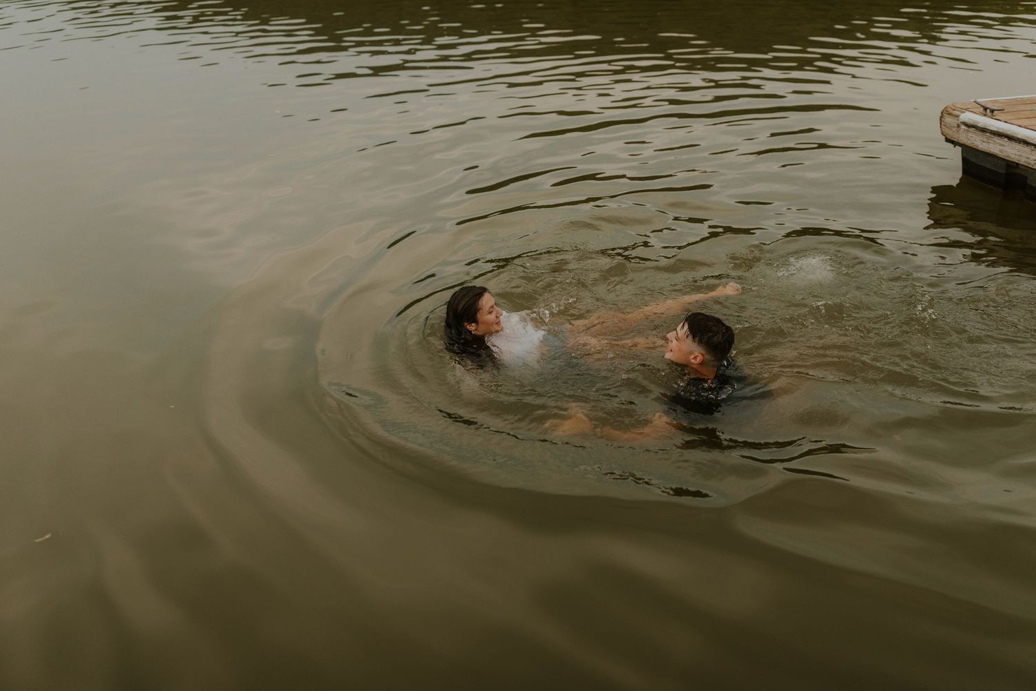 Swimmers playing in rippling lake water on an overcast day.