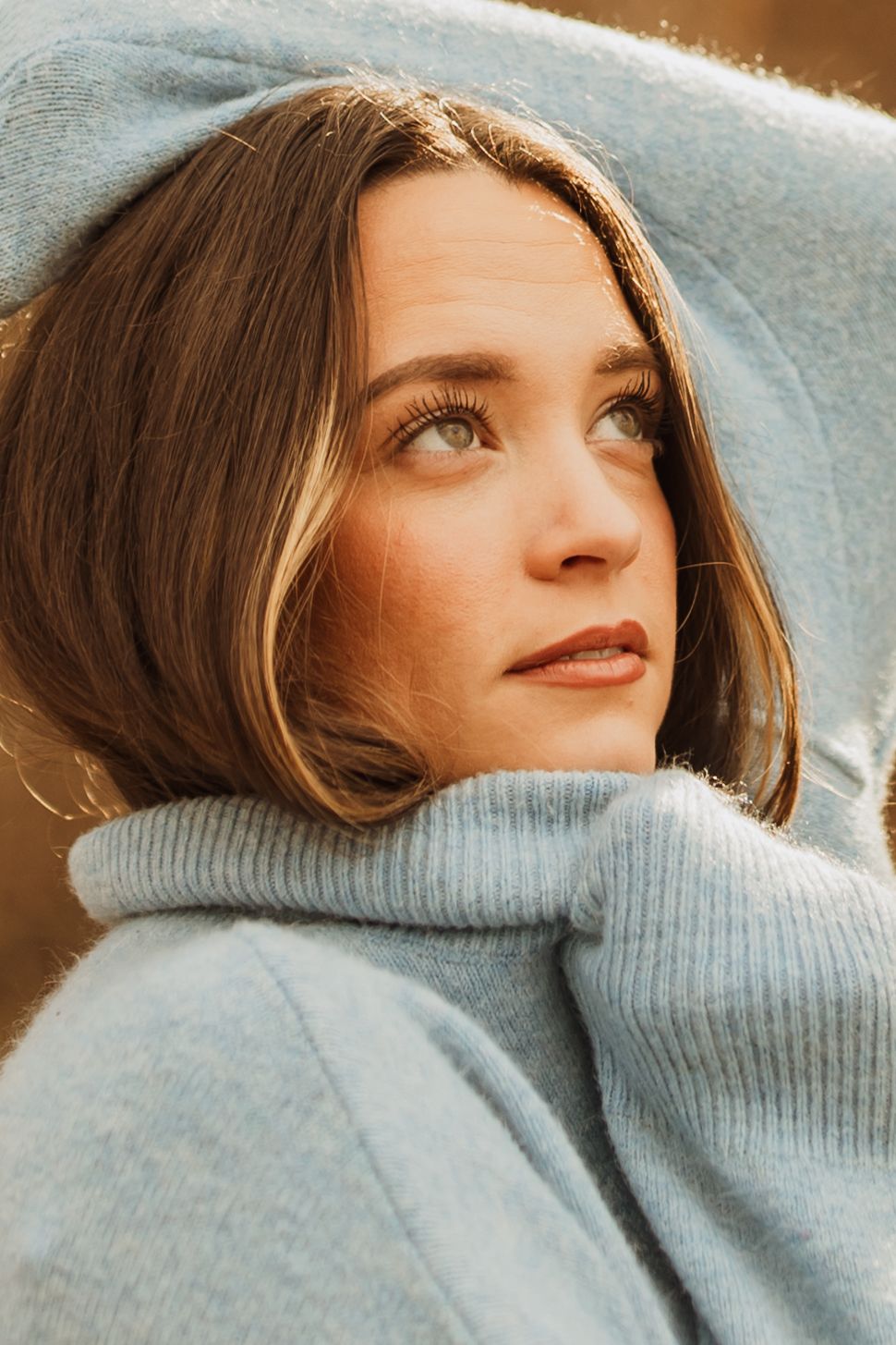 Portrait of someone wearing a cozy gray sweater looking up thoughtfully.