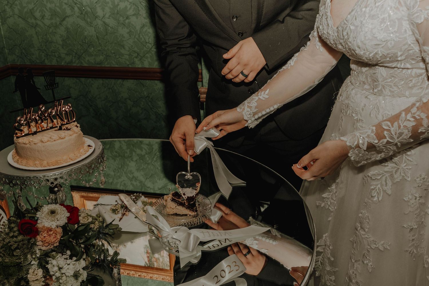 Wedding cake cutting scene with elegant table settings and floral decorations.
