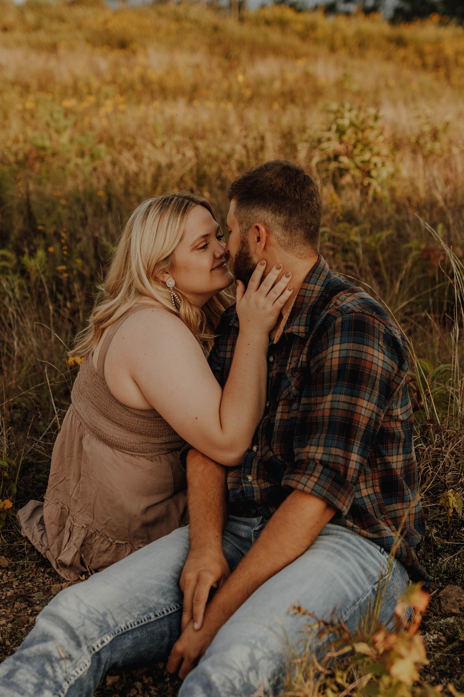 Couple sharing an intimate moment in a golden field at sunset.