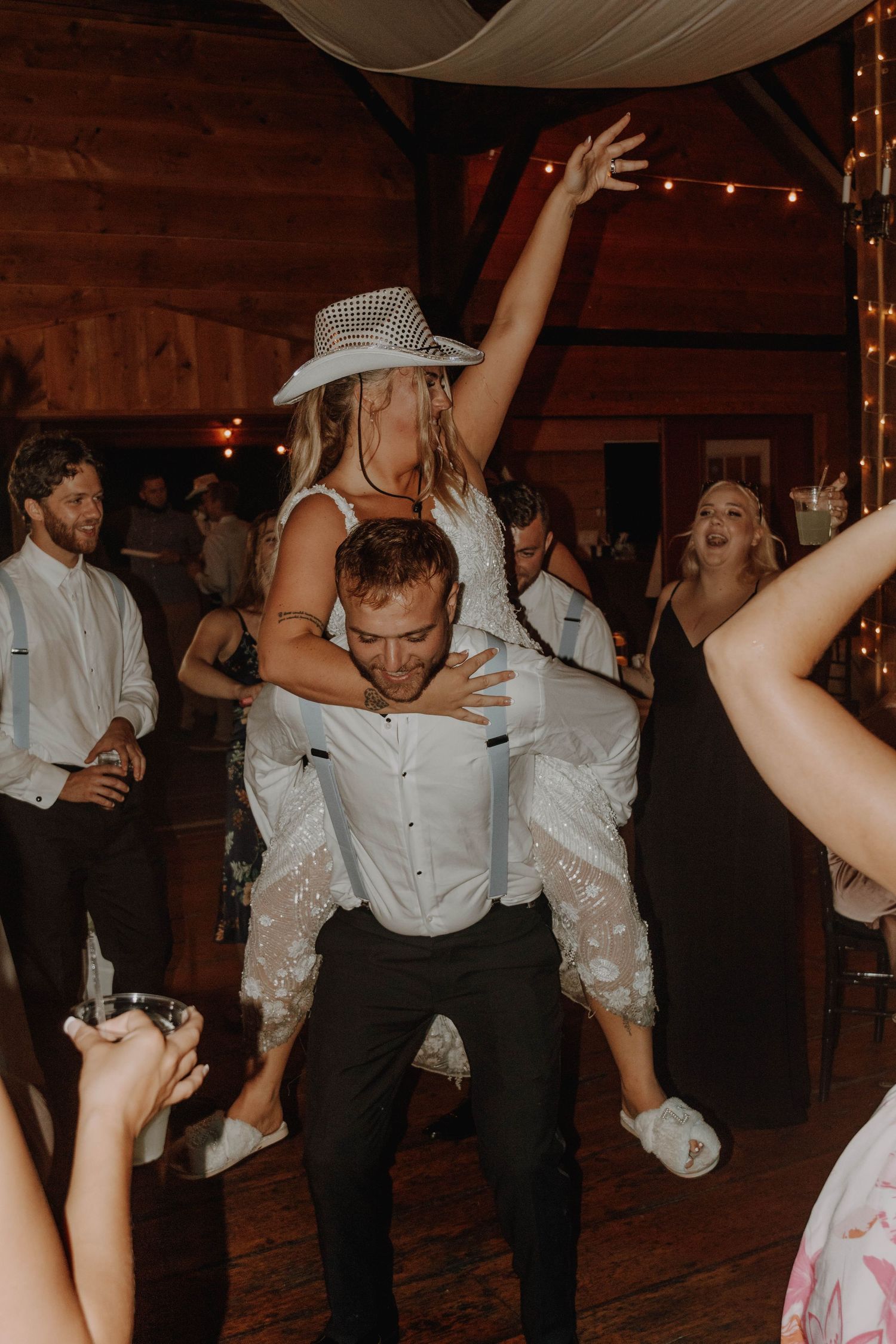Lively wedding reception dance moment with partygoers in rustic barn venue.